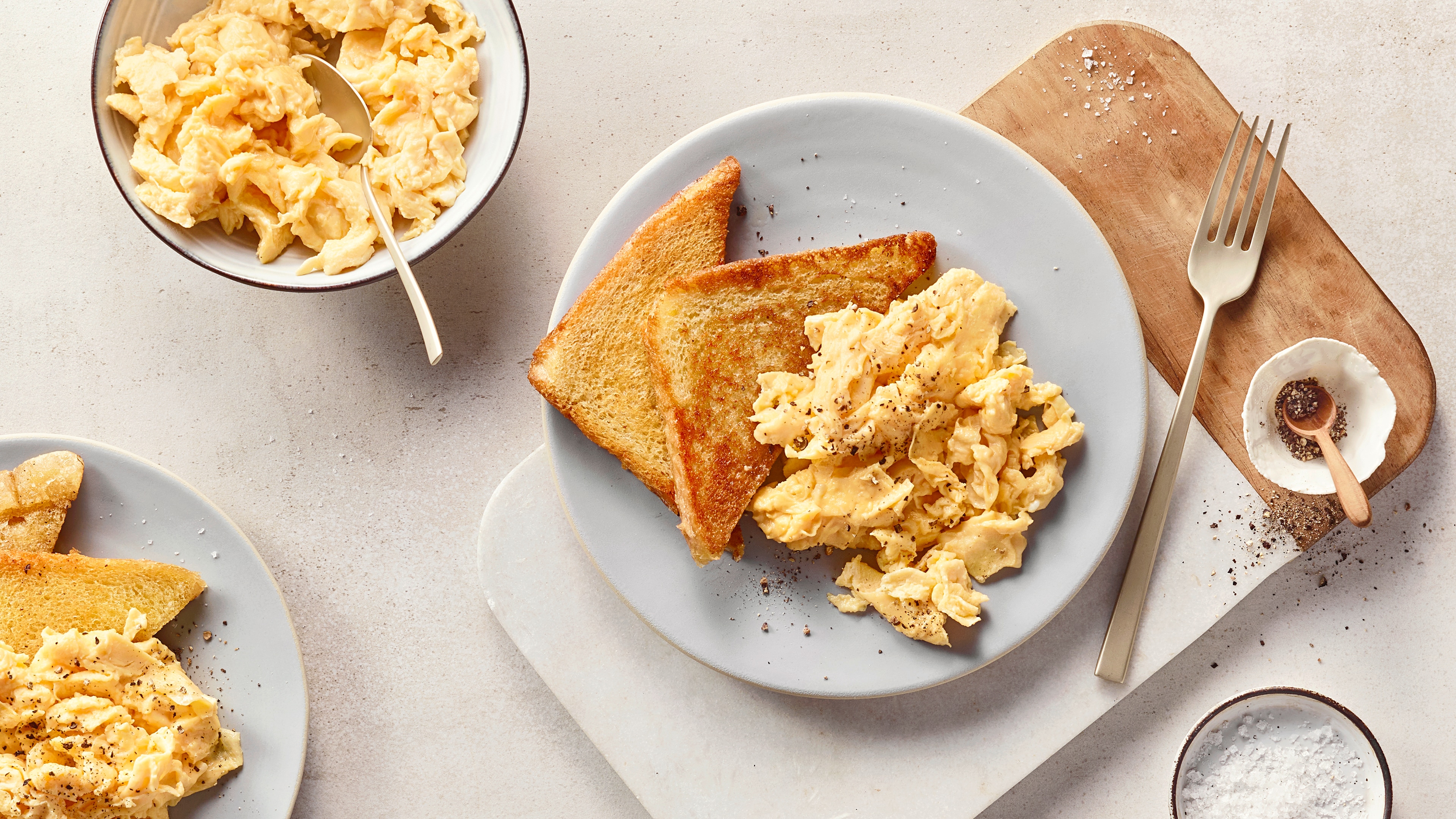 Ein Teller mit gelbem Rührei, bestreut mit Pfeffer, daneben zwei goldbraune Toastscheiben.