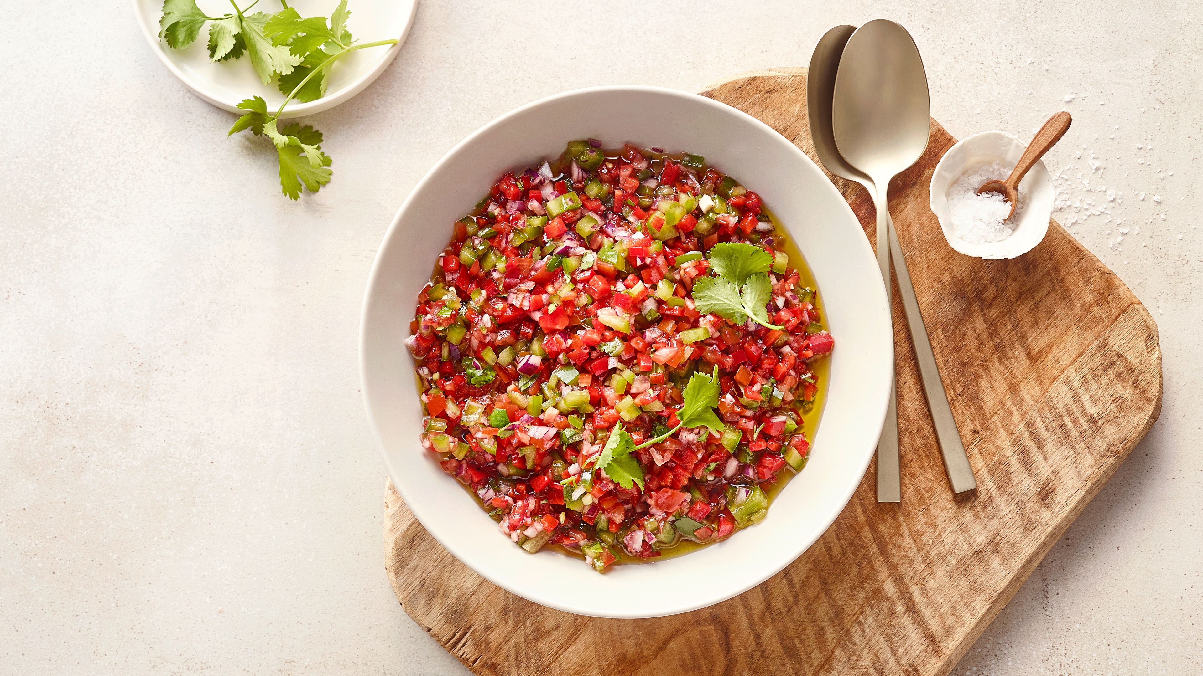Große Schale mit kleinen roten, grünen und lilanen Stücken in Öl, daneben Koriander