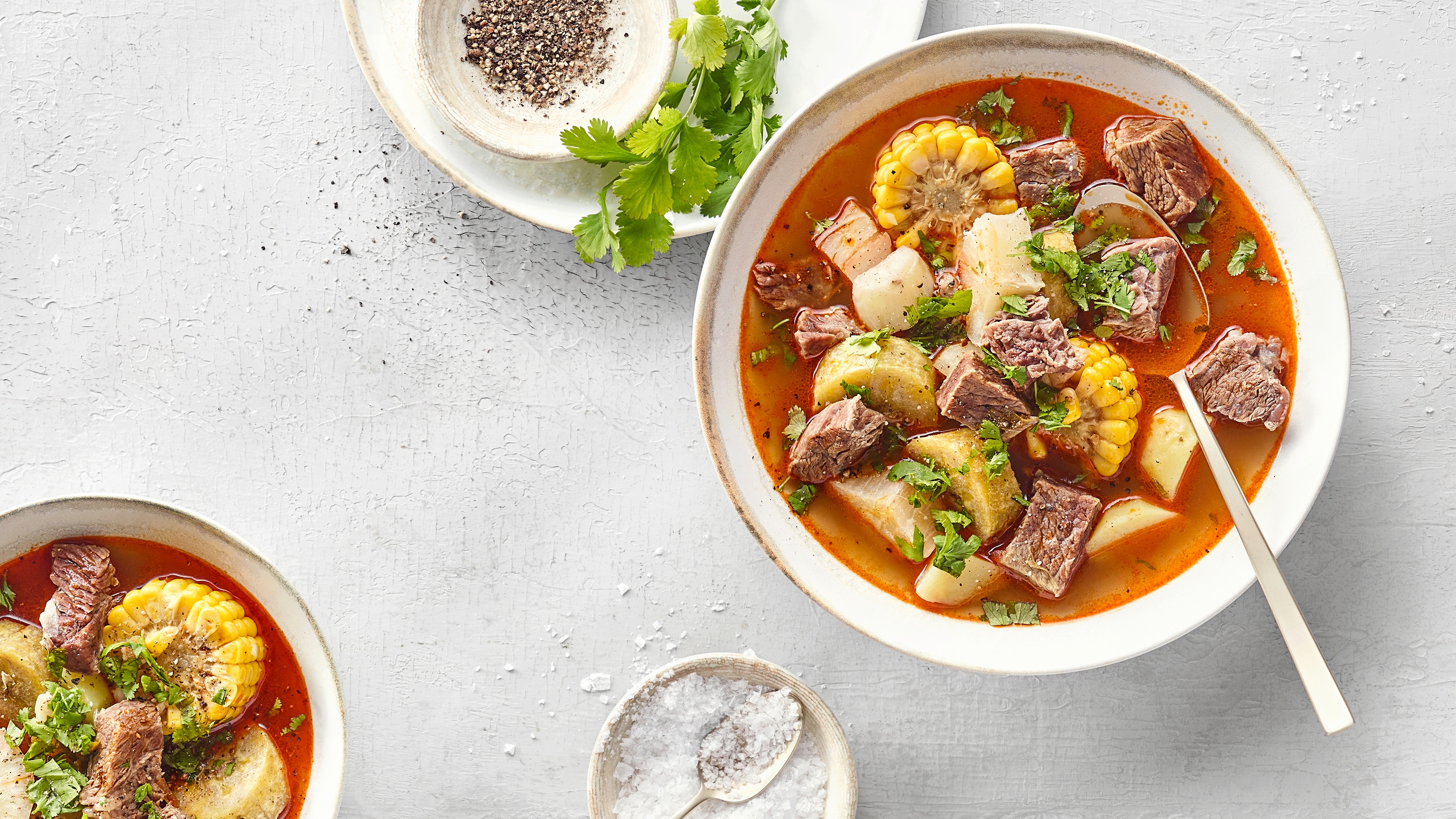 Brühiger Eintopf aus Fleisch, Wurzelgemüse, Maisscheiben und Koriander.
