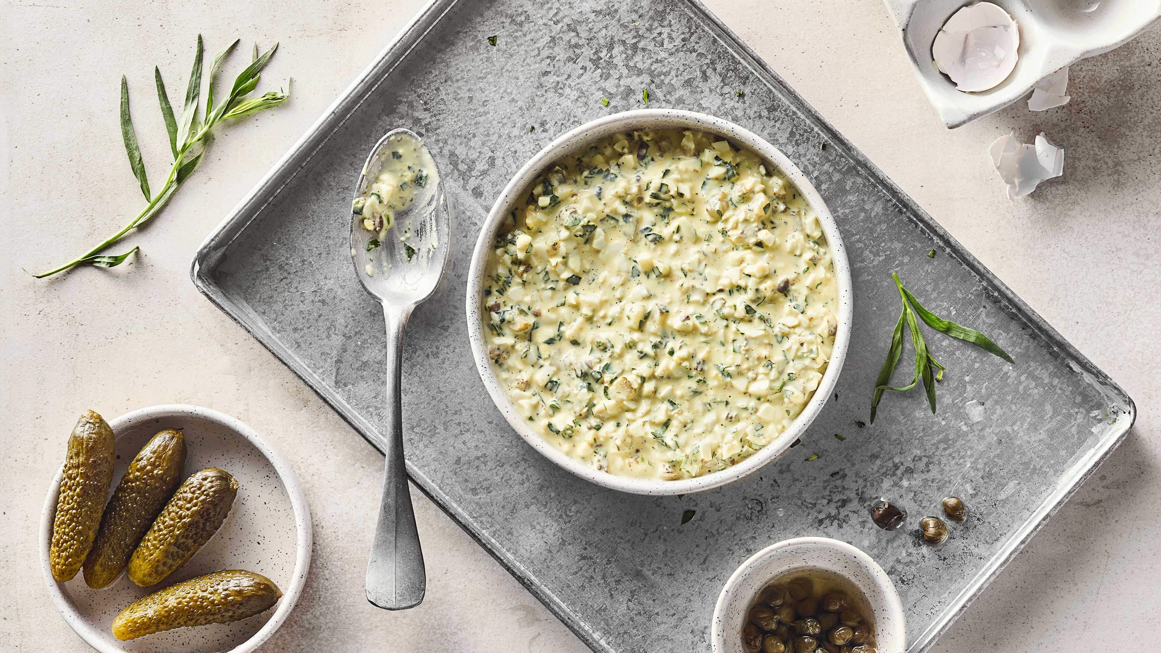 Rezept für Sauce Gribiche Ein runder Teller mit cremiger Sauce mit Kapern, Gewürzgurken- und Ei-Stückchen