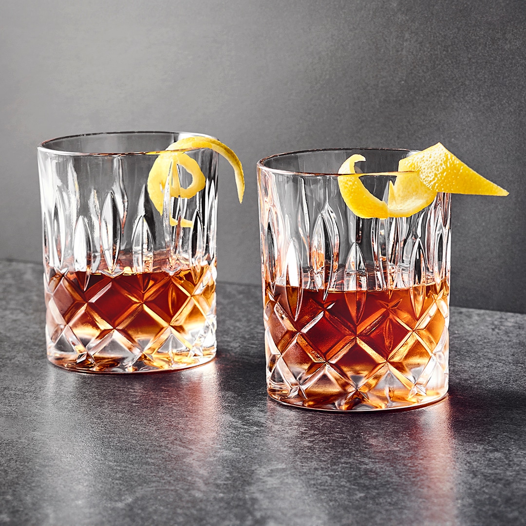 Zwei halbgefüllte Cocktailgläser mit jeweils einer Zitronenschale.
