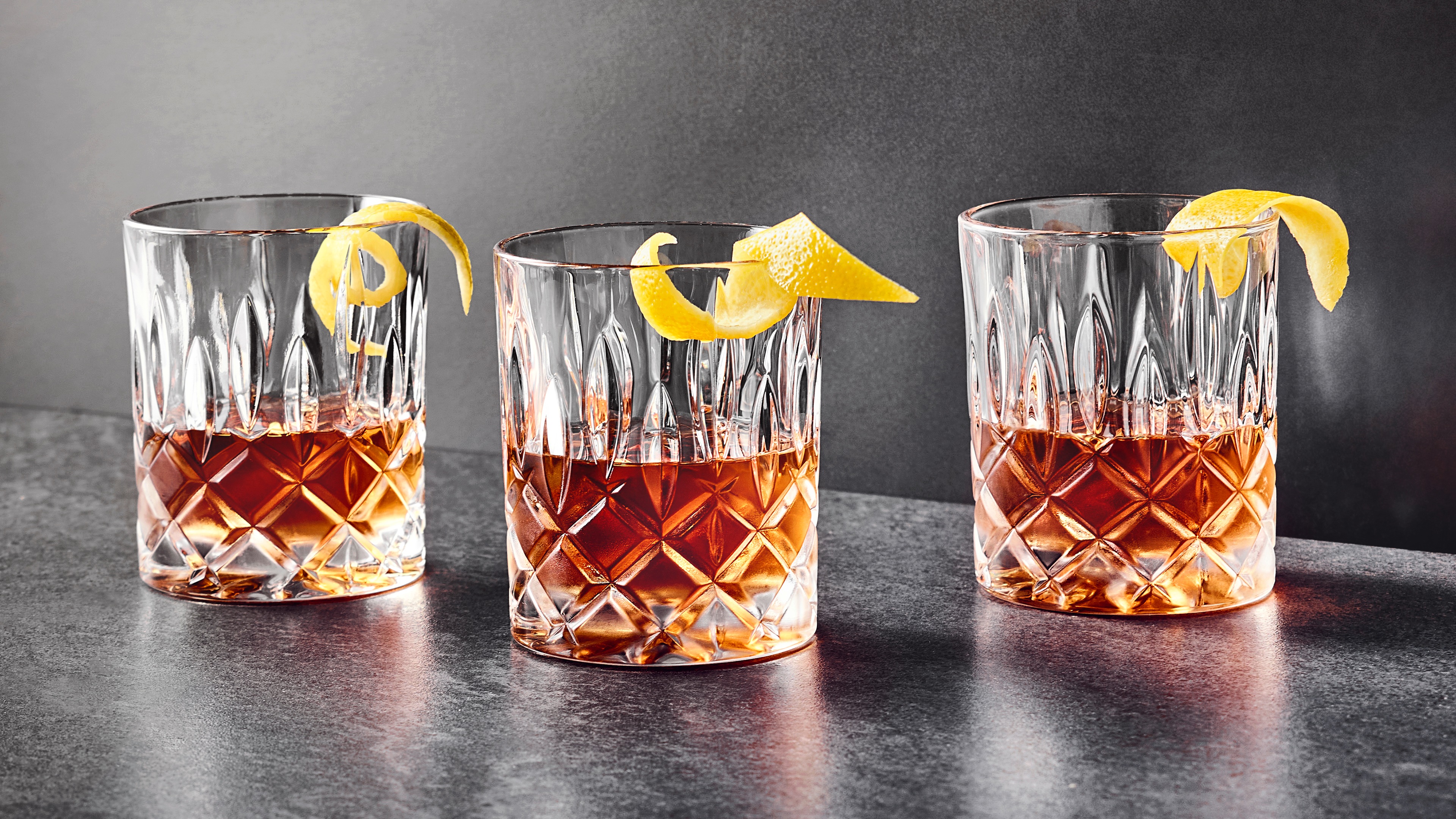 Drei halbgefüllte Cocktailgläser mit jeweils einer Zitronenschale.