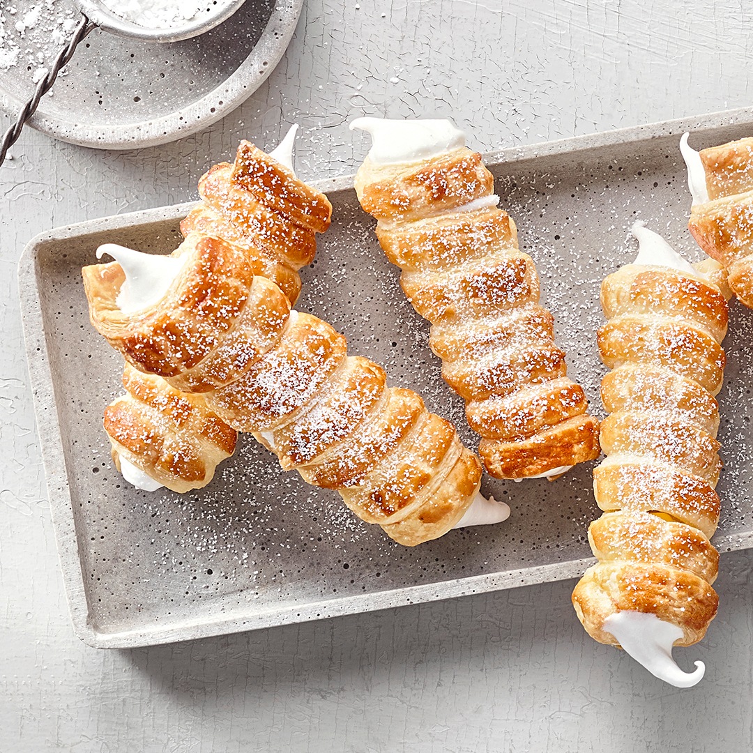 Knusprige Schaumrollen aus goldenem Blätterteig, gefüllt mit luftiger, weißer Vanillecreme.