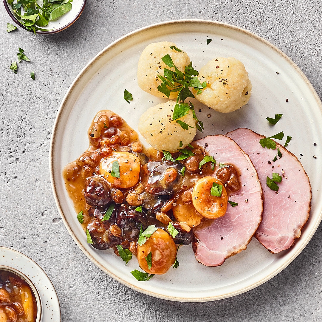 Fleischgericht bestehend aus geräuchertem Schweinebauch, Backobst und Semmelknödeln, verfeinert mit Petersilie.