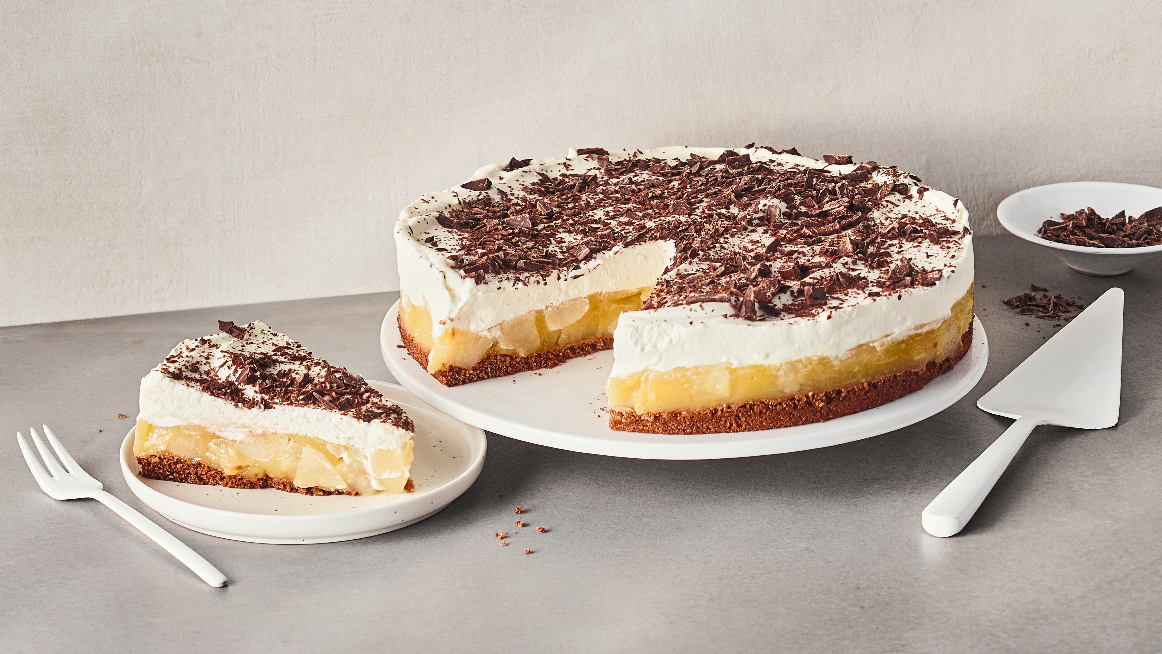 Auf Tellern eine Torte mit einem Schokoboden, Birnen und einer sahnigen Creme, garniert mit geraspelter Zartbitterschokolade