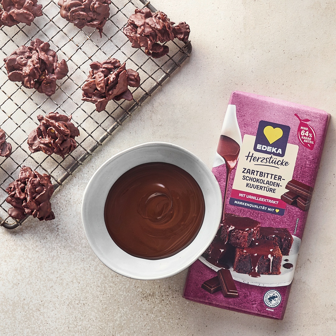 Ein Teller mit weißen und braunen Schoko-Clustern aus knusprigen Zutaten, daneben eine Schale mit flüssiger Schokolade