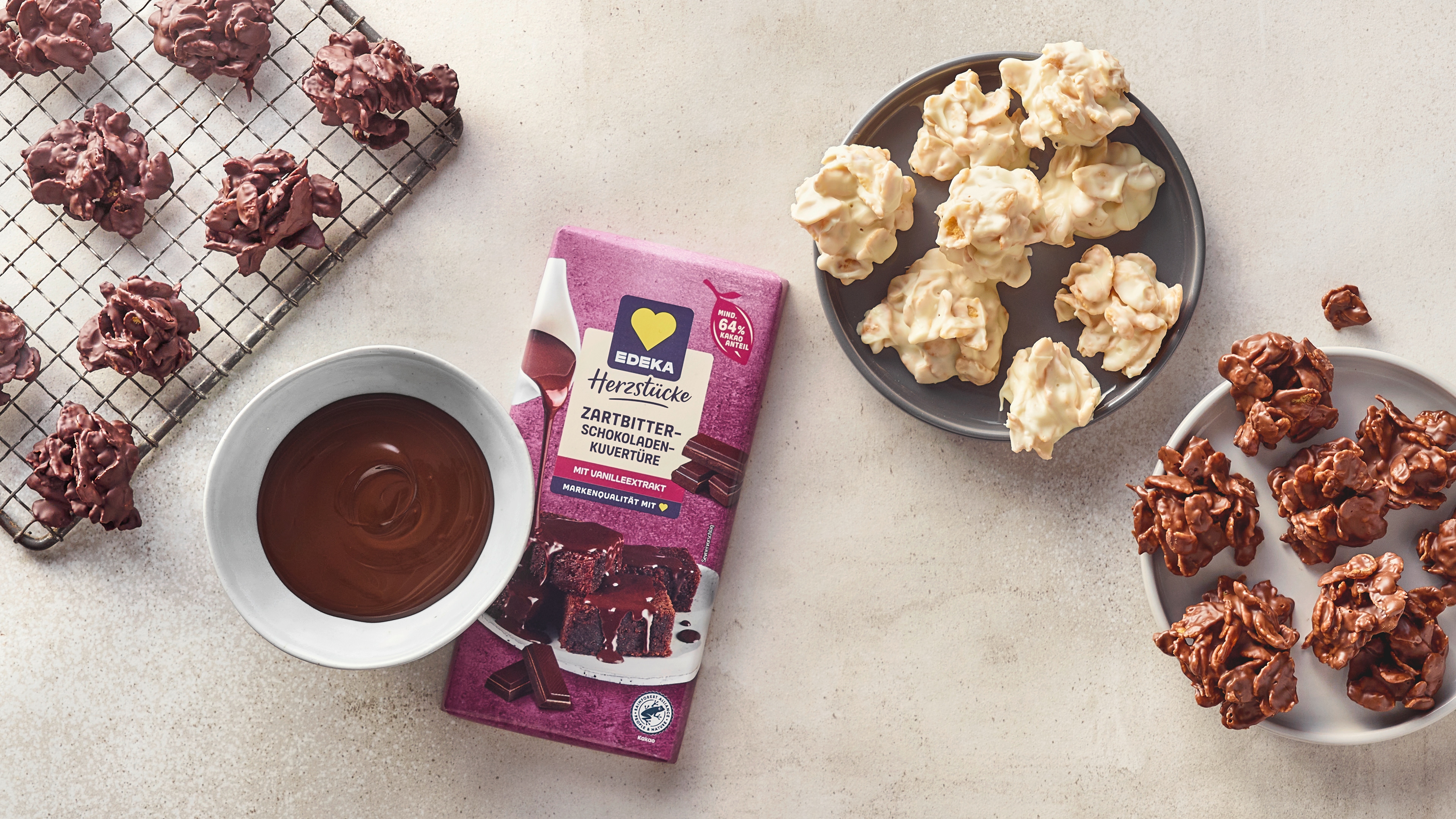 Ein Teller mit weißen und braunen Schoko-Clustern aus knusprigen Zutaten, daneben eine Schale mit flüssiger Schokolade