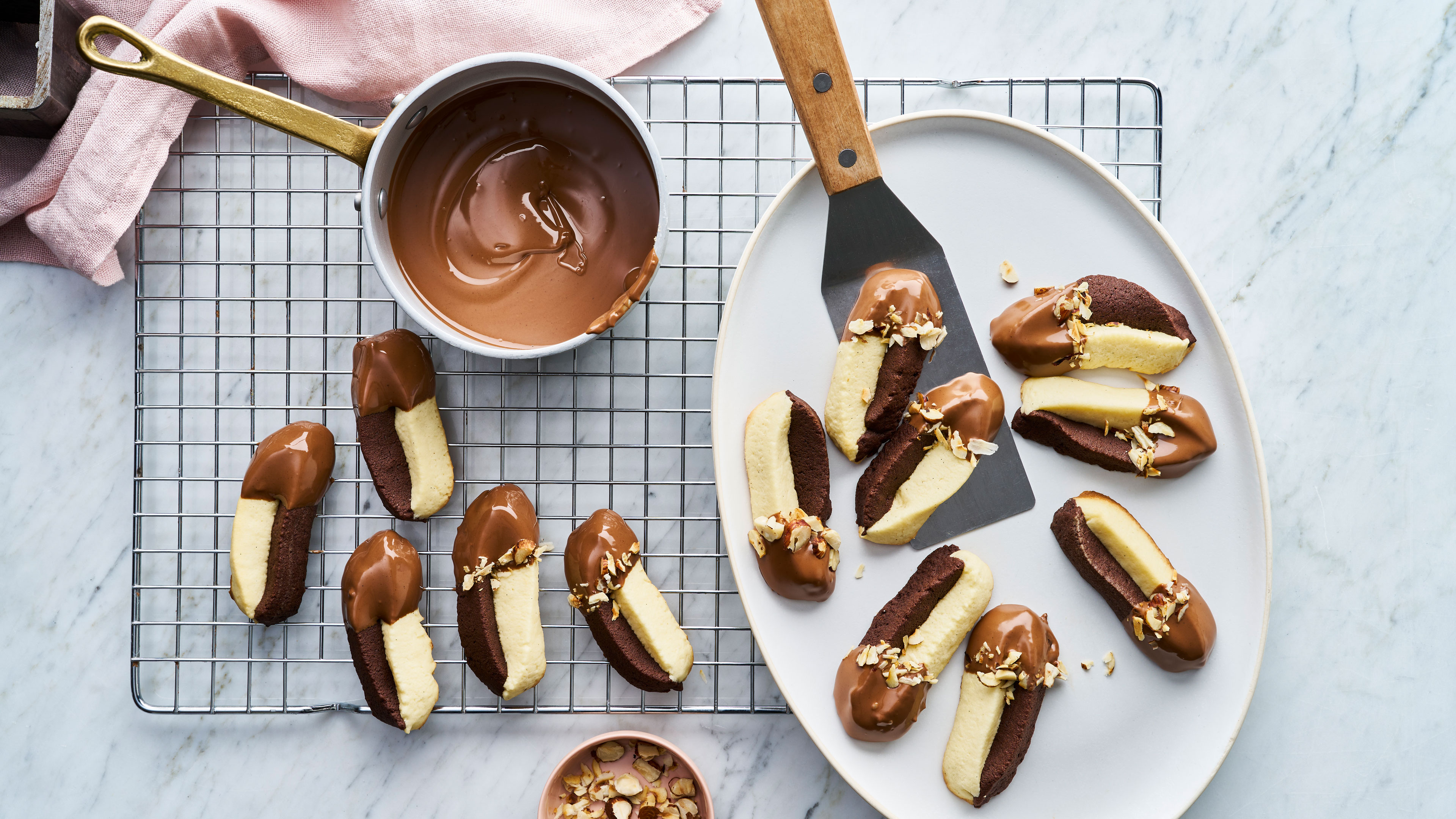 Rezept für Schwarz-Weiß-Spritzgebäck mit Nougat Zweifarbige längliche Kekse mit halbem Schokoladenüberzug auf Gitter und Teller