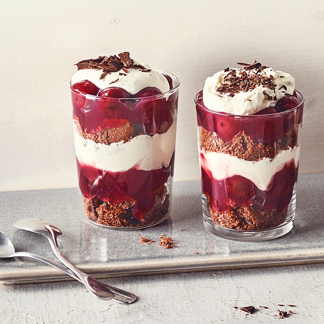 Dessertgläser, abwechseld befüllt mit Schichten aus Schokocreme, Kirschkompott und Sahnecreme, getoppt mit Schokoraspeln