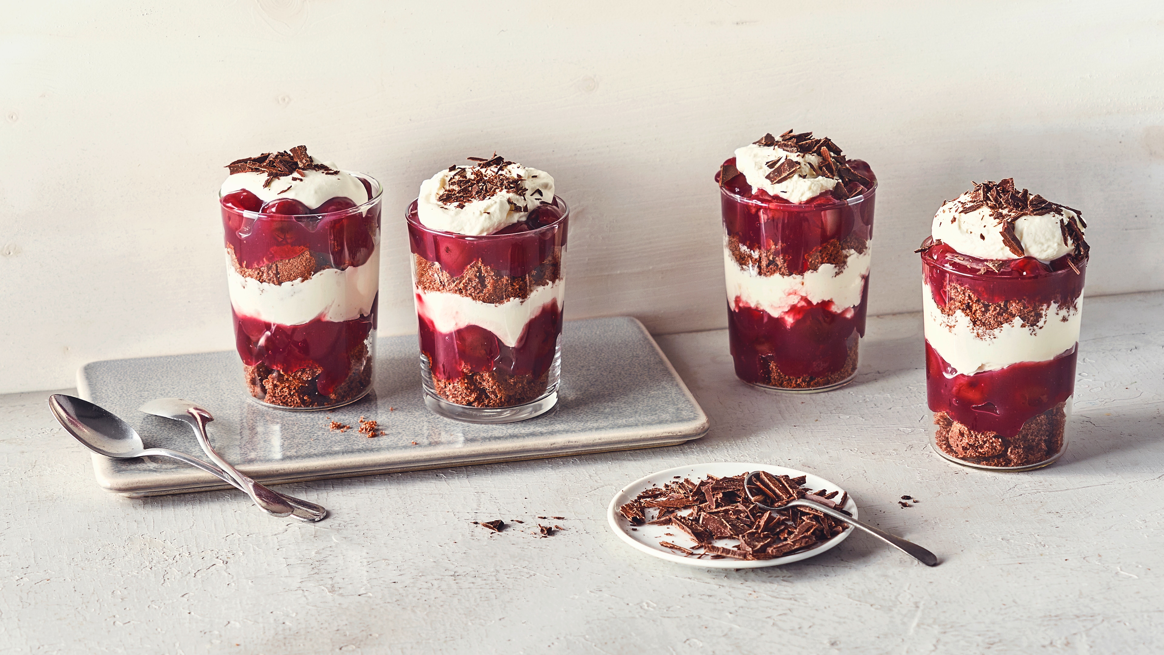 Rezept für Schwarzwälder-Kirsch-Dessert Dessertgläser, abwechseld befüllt mit Schichten aus Schokocreme, Kirschkompott und Sahnecreme, getoppt mit Schokoraspeln