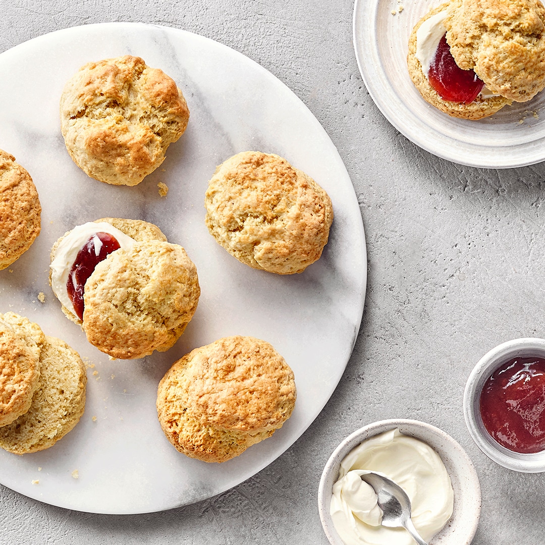 Fünf Scones auf Teller, serviert mit Clotted Cream und Marmelade
