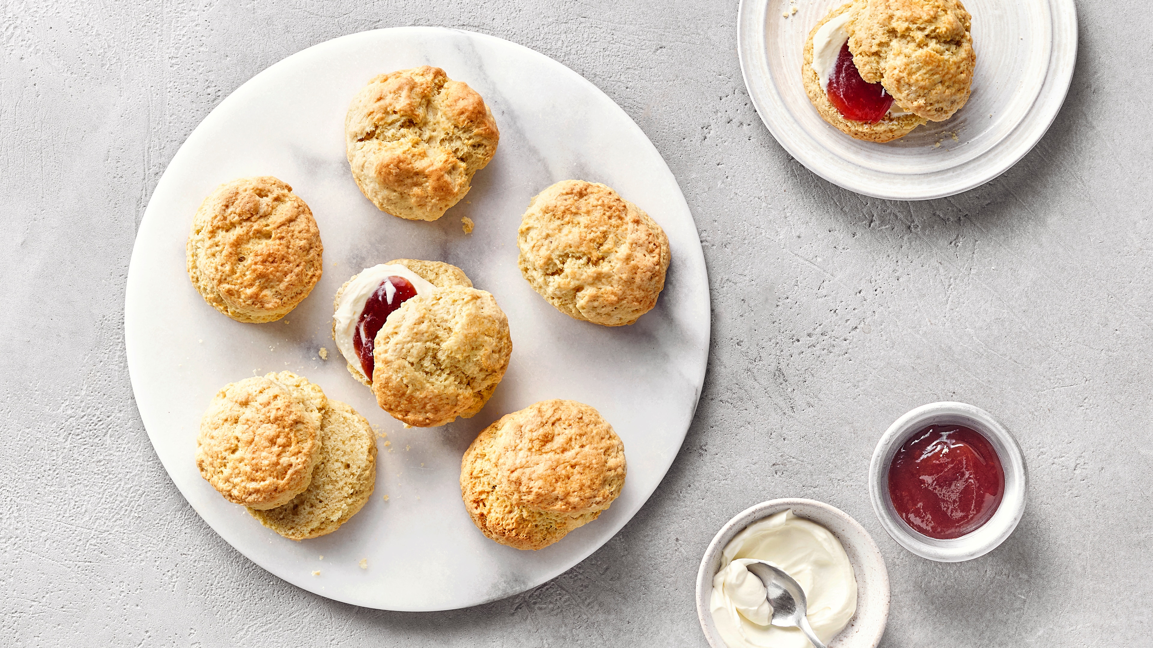 Fünf Scones auf Teller, serviert mit Clotted Cream und Marmelade