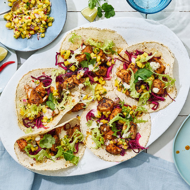 Offene Tacofladen mit Fischstücken  und Salat auf großem Teller