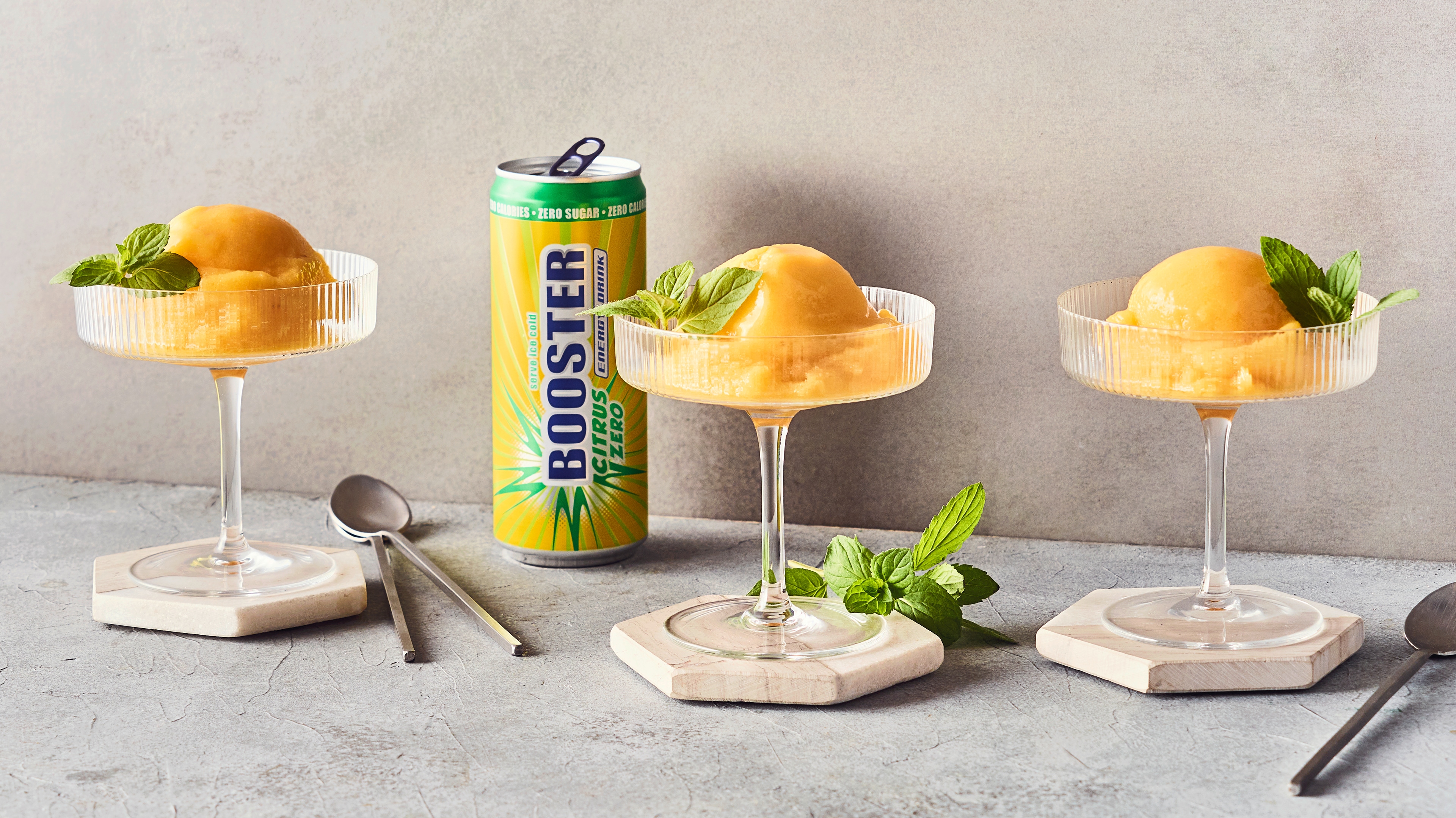 Rezept für Sorbet mit Booster Citrus Zero Energy Drink Zitronengelbes gefrorenes Fruchtpüree, getoppt mit frischen Minzblättern, in geriffelten Glasschalen