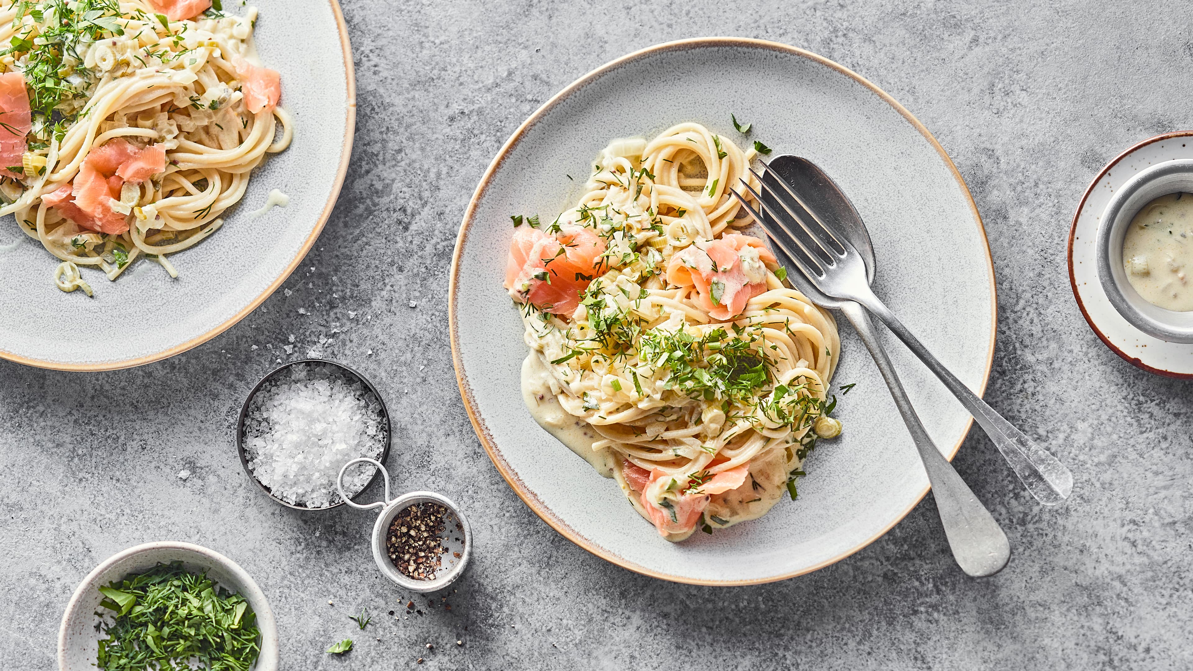 Rezept für Spaghetti mit Räucherlachs Ein runder Teller mit cremigen Zitronen-Spaghetti mit Räucherlachs, getoppt mit frischem Dill und Petersilie