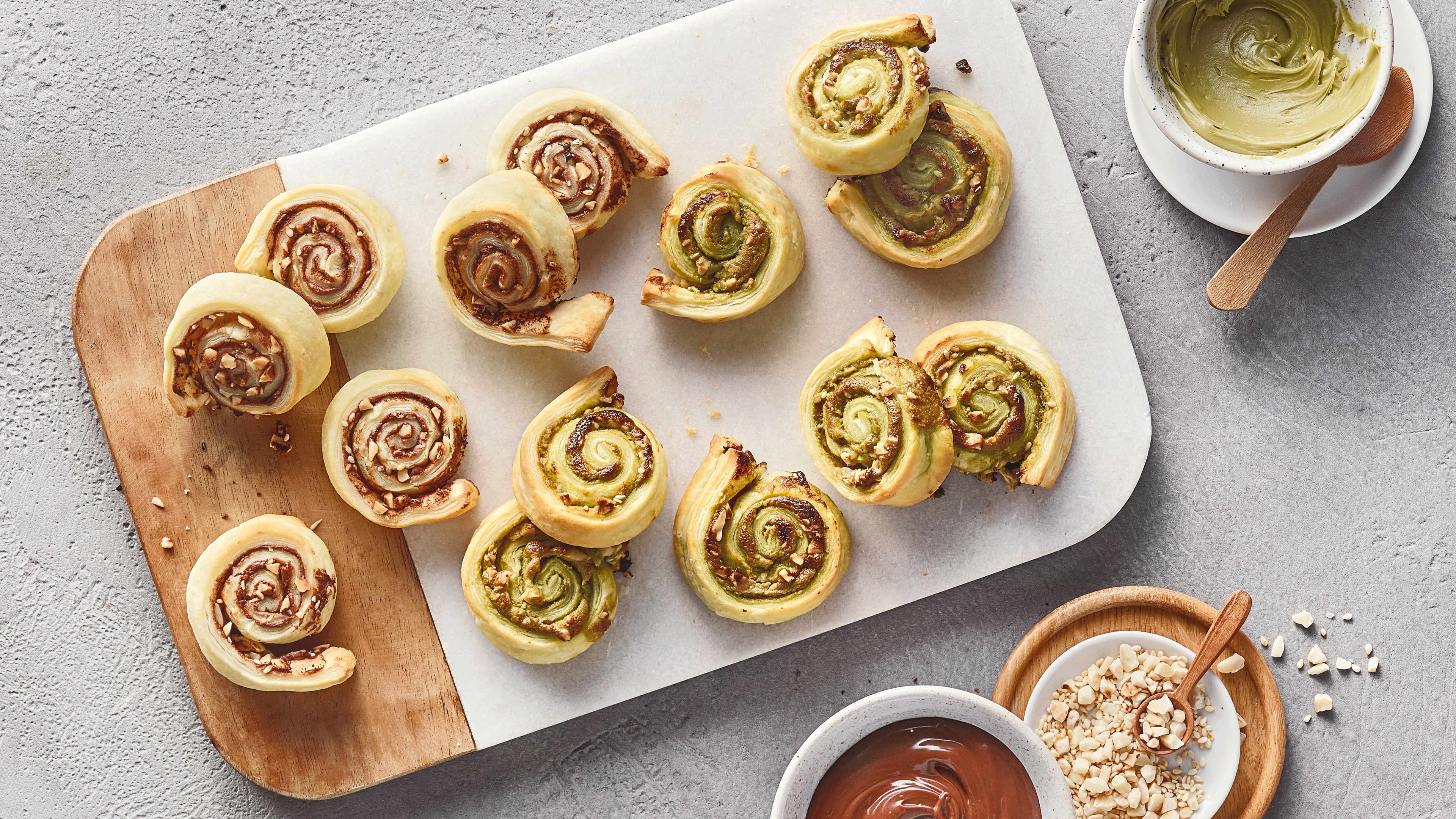 Ein Brett mit gebackenen Blätterteig Röllchen, gefüllt mit Pistazien- und Schokocreme.