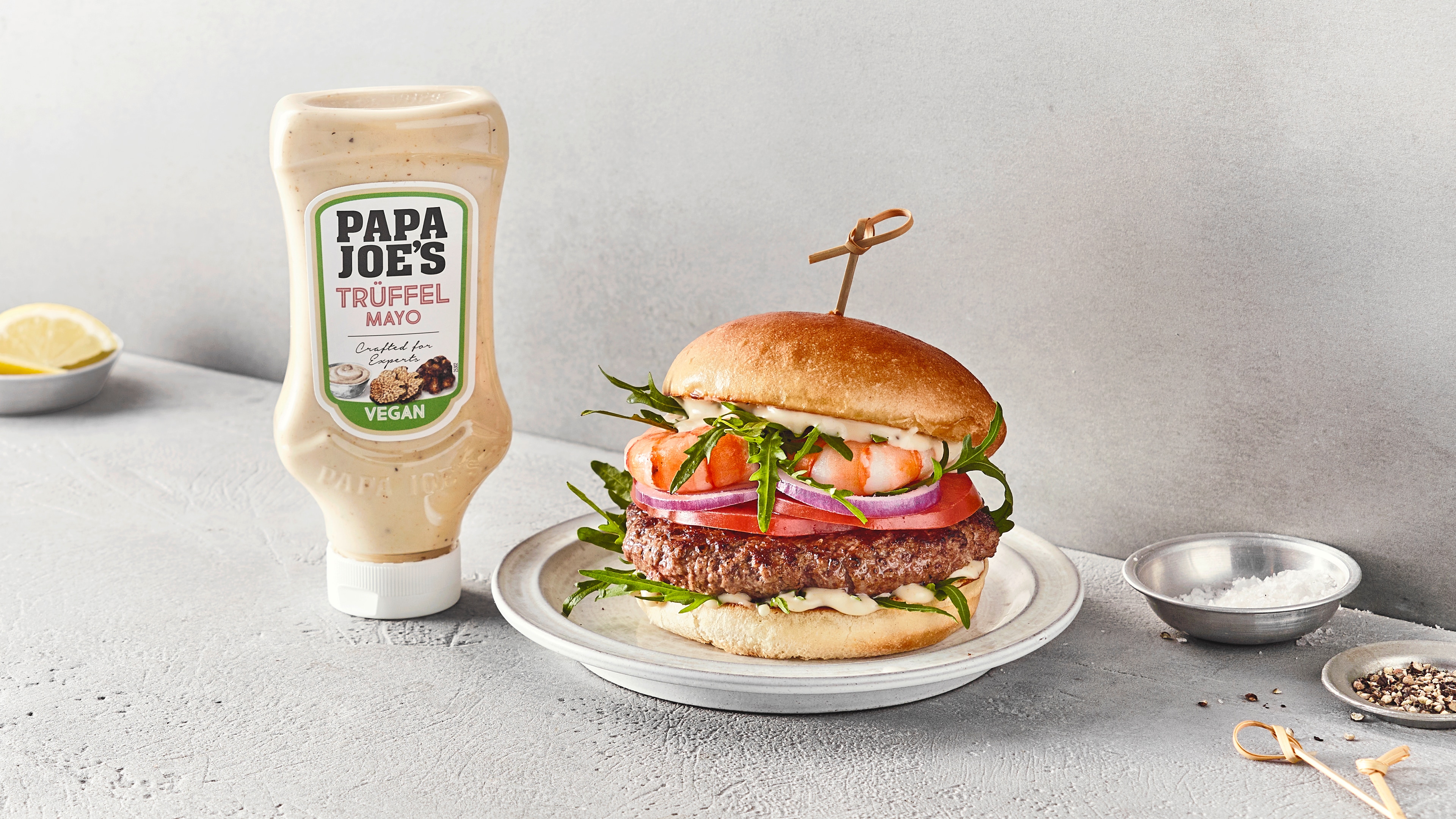 Burger mit Patty, Tomaten und Garnelen auf Teller, daneben Papa Joes Trüffelmayonnaise