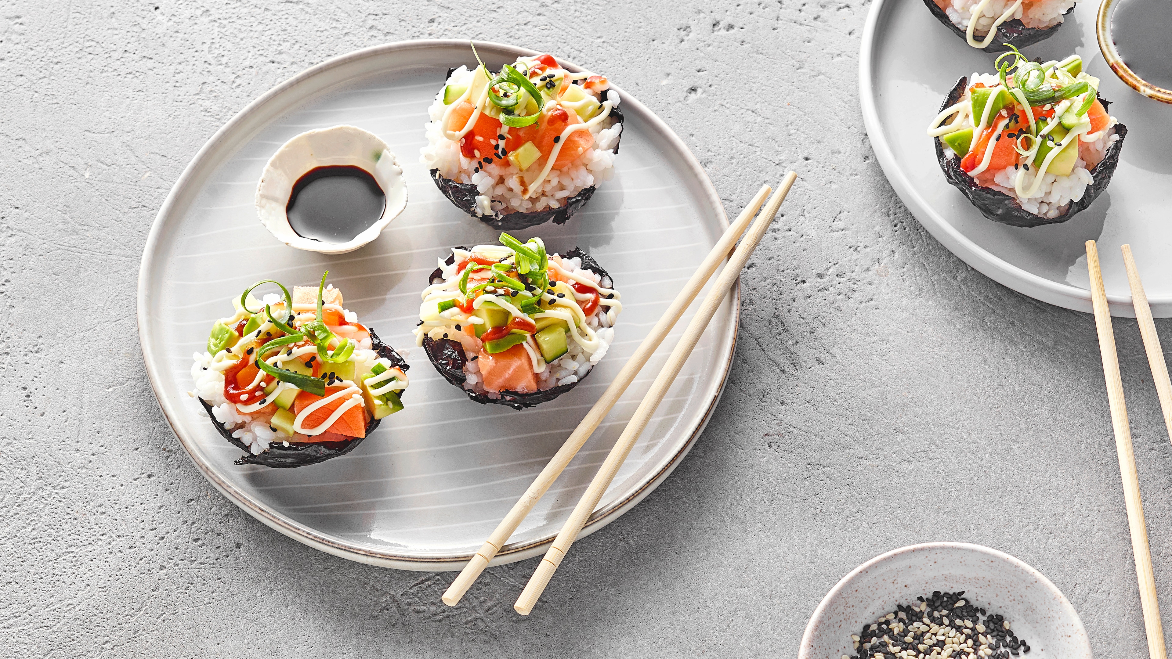 Kleine, runde Sushi‑Muffins aus in einer Muffinform gepresstem Reis, belegt mit rohem Lachs, Avocado und Sesam.