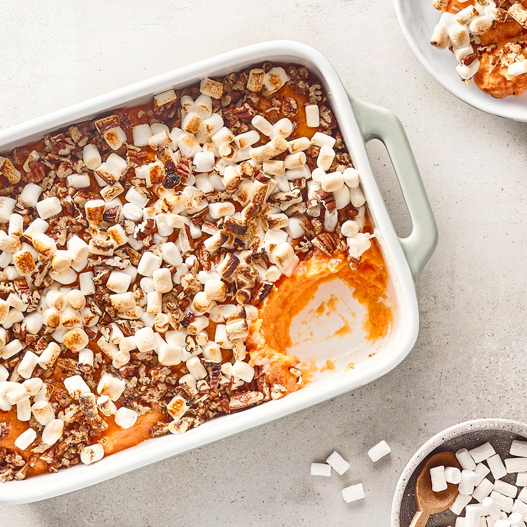 Auflaufform mit orangem Püree, Nüssen und kleinen Marshmallows