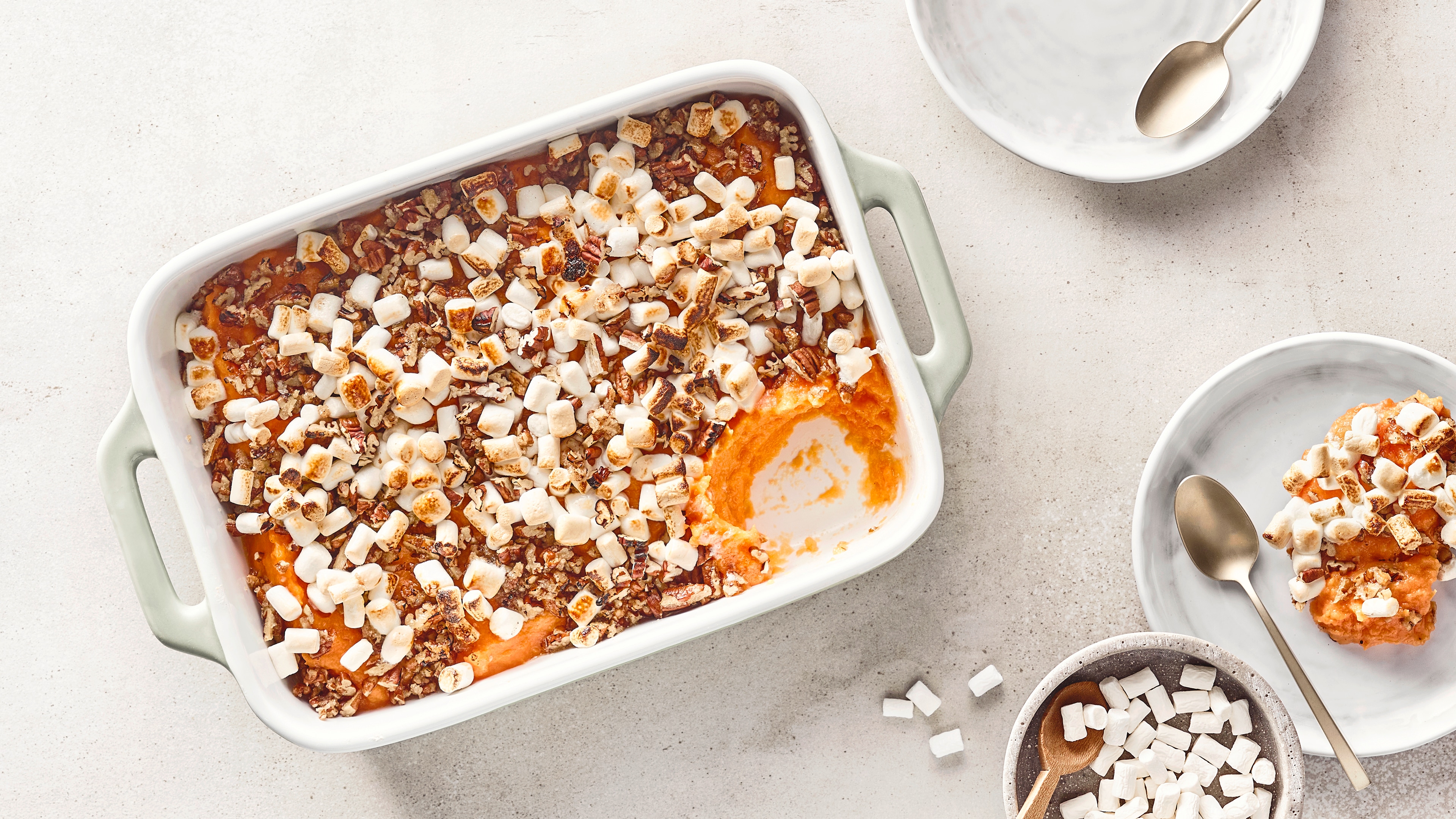 Auflaufform mit orangem Püree, Nüssen und kleinen Marshmallows