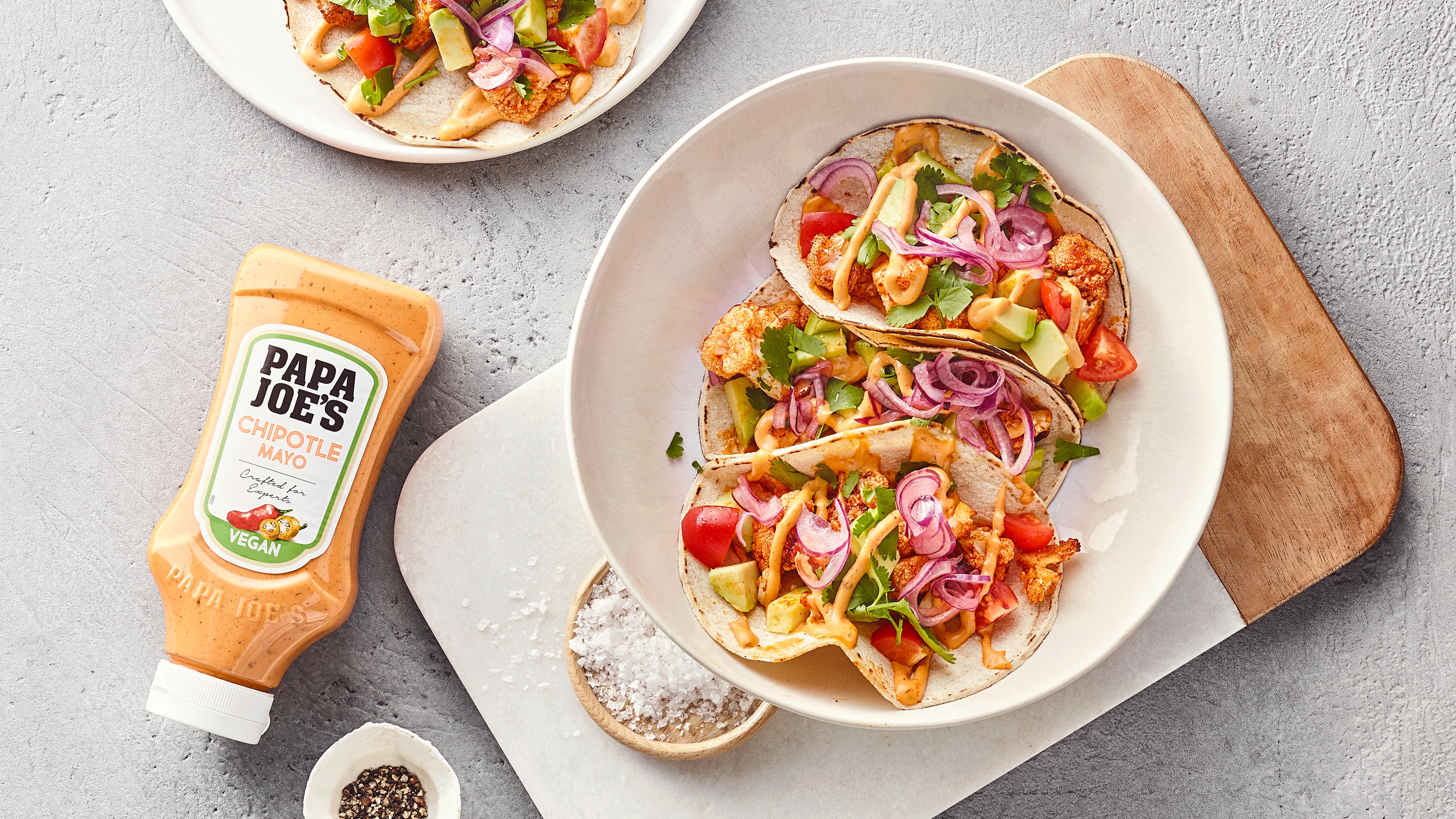 Offene Tacofladen mit Zwiebeln, Blumenkohl, Kräutern und Soße, daneben Papa Joe's Chipotle Mayonnaise