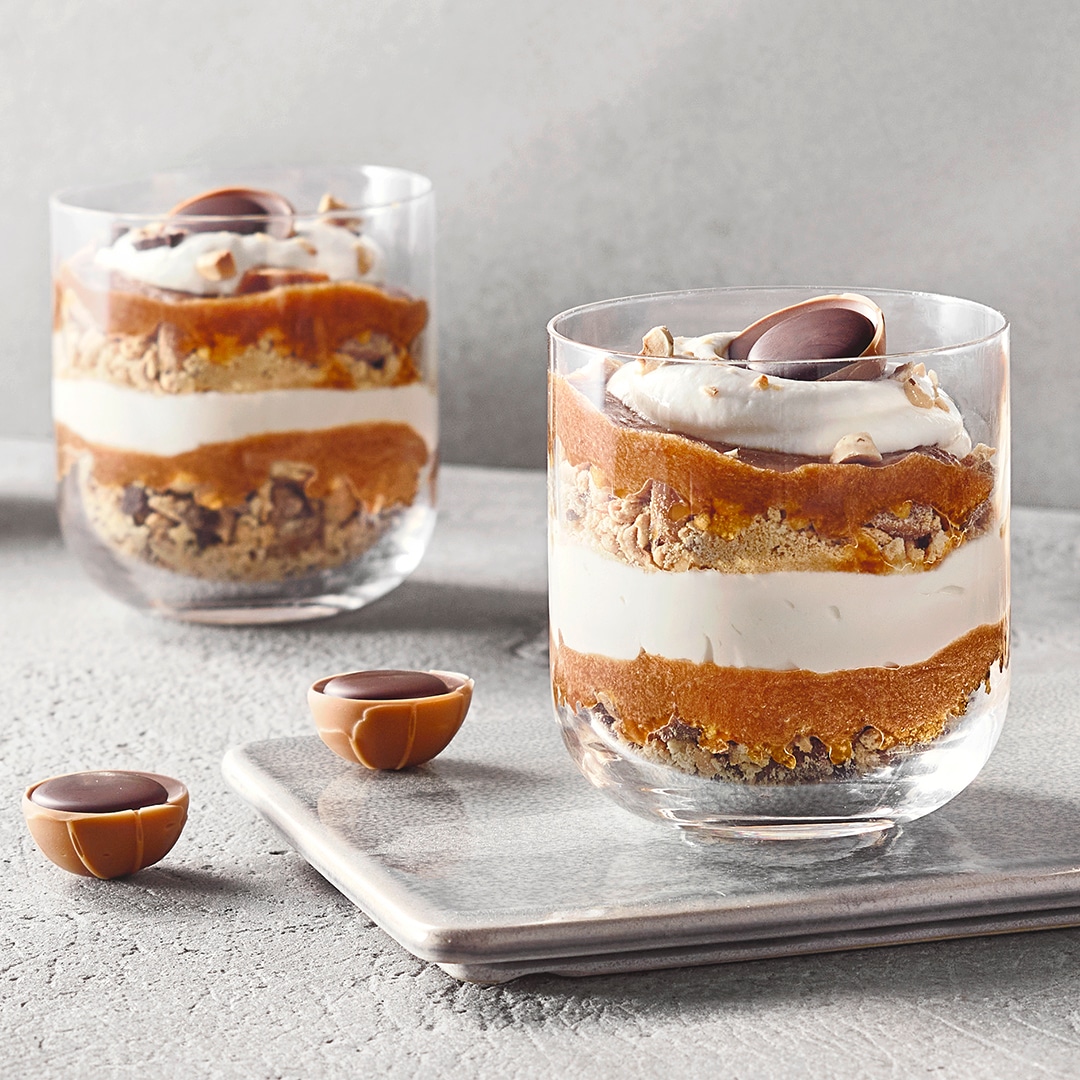 Zwei Dessertgläser mit Toffifee-Pralinen und Schichten aus Creme, Keksboden und Karamell.