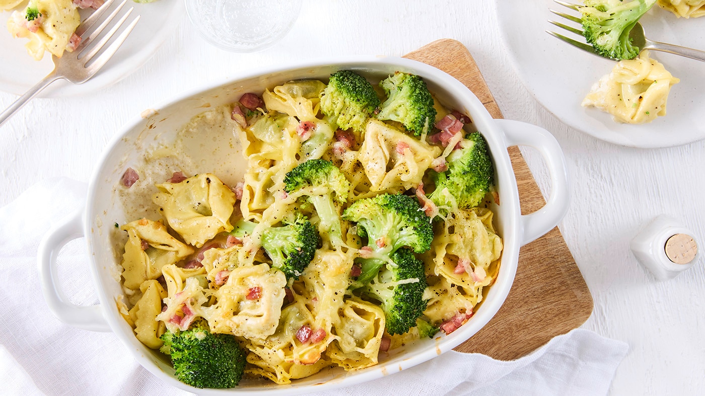 Tortellini-Auflauf mit Brokkoli, Schinken und cremiger Käsesoße in einer Auflaufform.