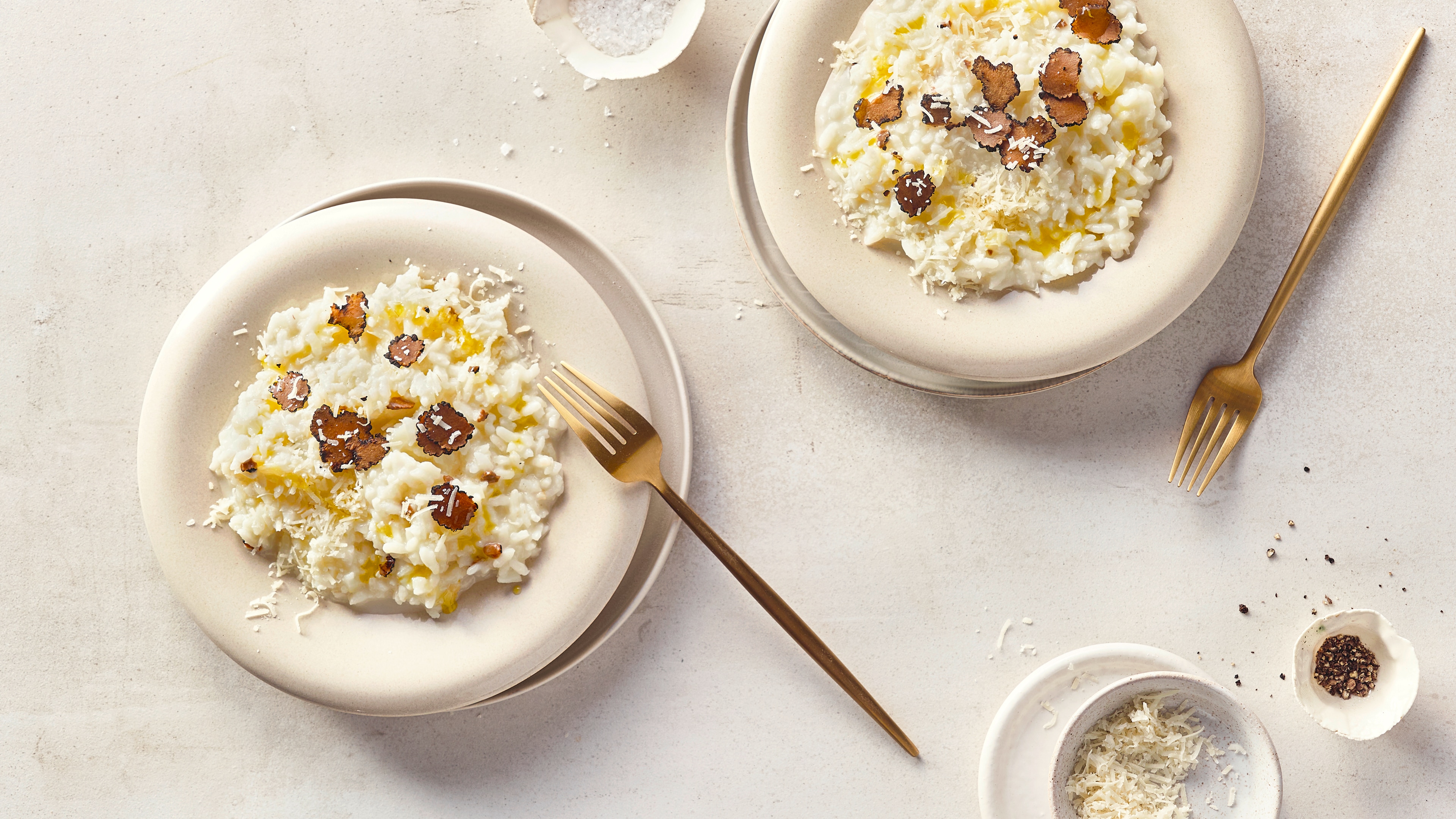 Runde Teller mit cremigem, buttrigem Reis, getoppt mit geriebenem Käse und Trüffelscheiben