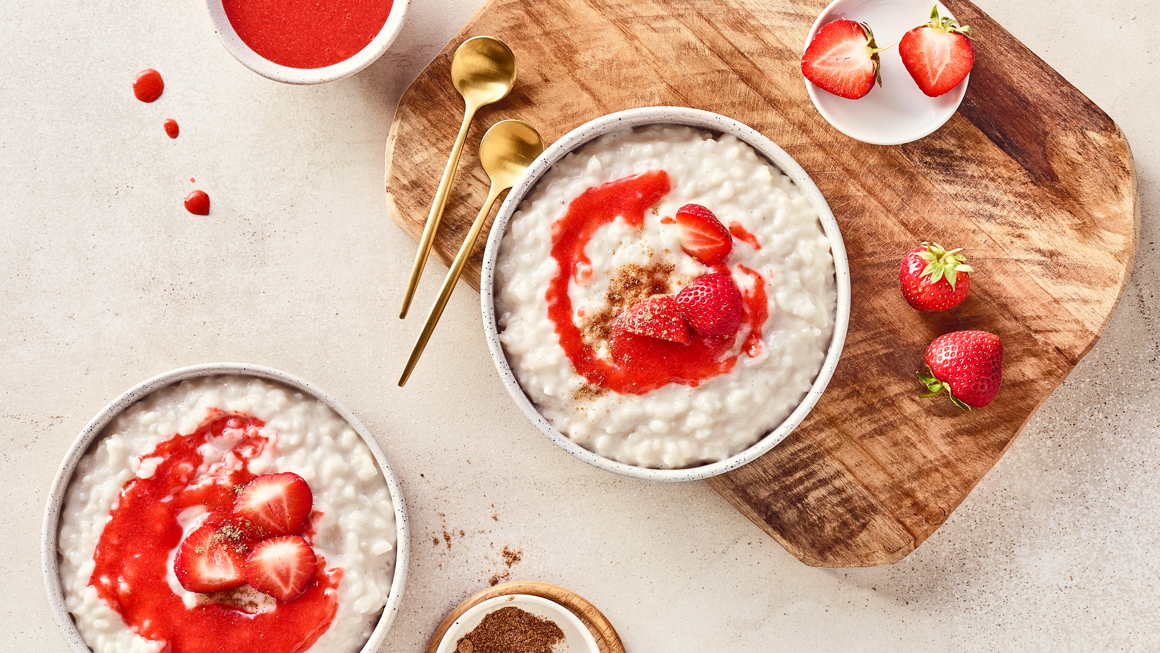Rezept für veganen Milchreis mit Erdbeeren Eine Schale mit cremigem reis, getoppt mit roter Soße, frischen Erdbeeren und einer Zimt-Zucker-Mischung