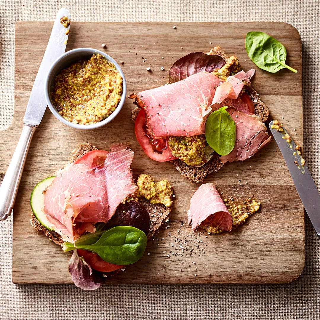 Vollkorn-Pastrami-Sandwich mit Tomate, Gurke und grobkörnigem Senf. Probieren Sie unser köstliches Vollkorn-Pastrami-Sandwich aus!