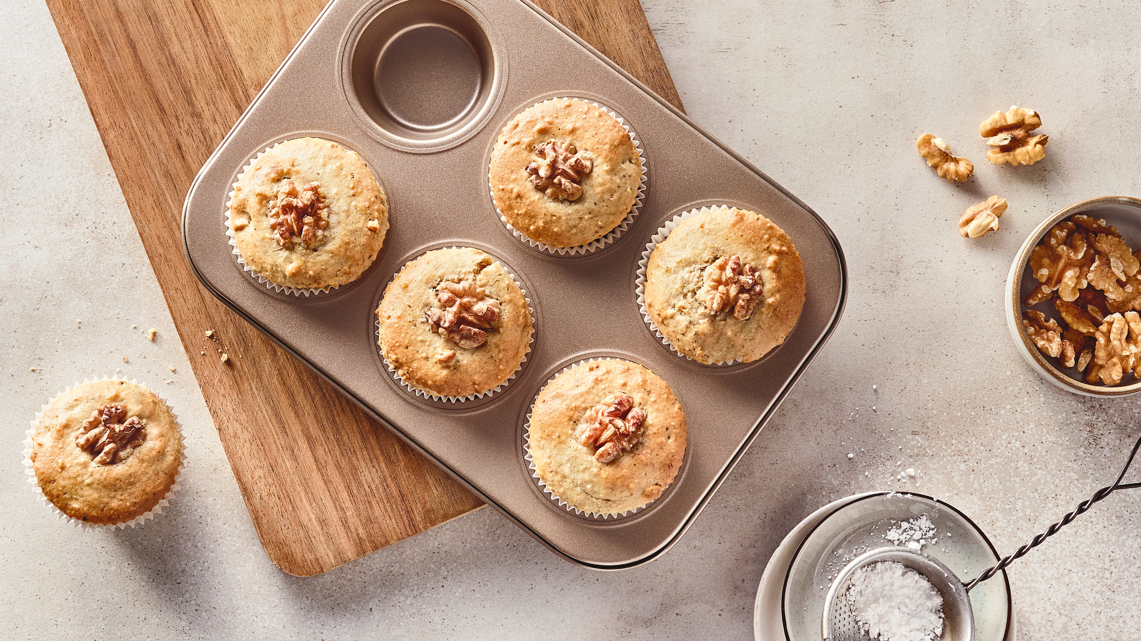 Rezept für Walnuss-Muffins Helle, gelbgold gebackene Muffins, getoppt mit ganzen Walnüssen, in einer Muffinbackform