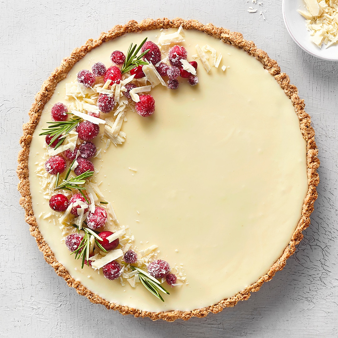 Heller Schokoladentarteboden mit weißer Schokocreme und roten Cranberries obenauf.