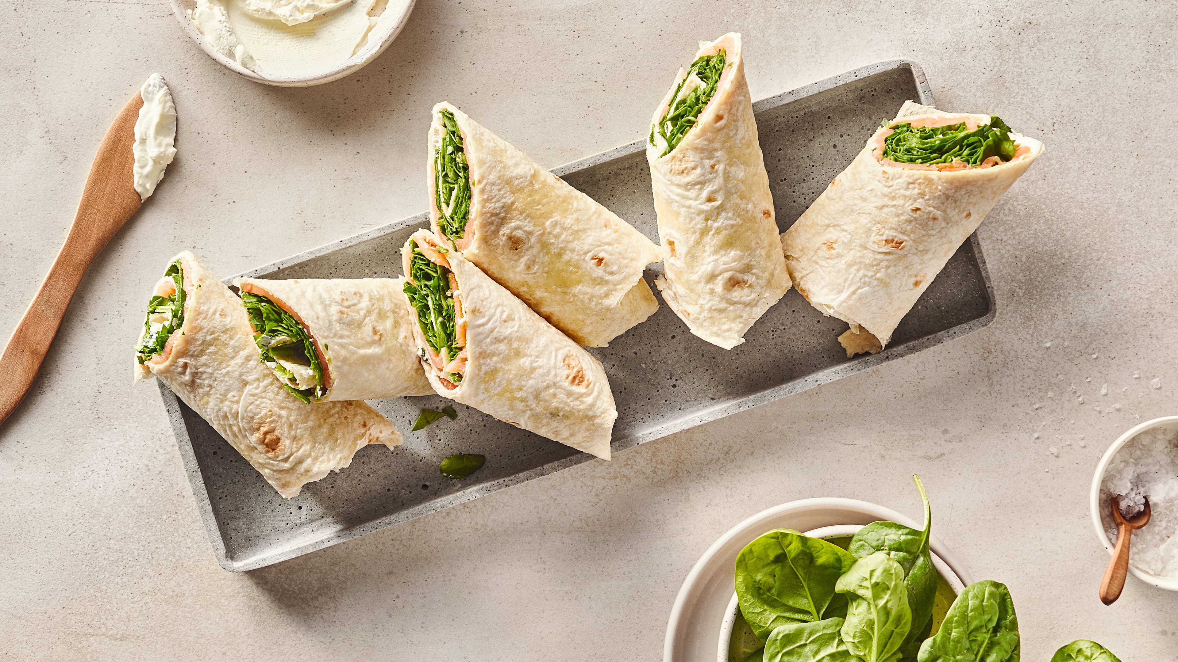 Rezept für Wraps mit Frischkäse und Lachs Wrap-Hälften gefüllt mit Salat, Lachs und Frischkäse, auf einem länglichen Tablett