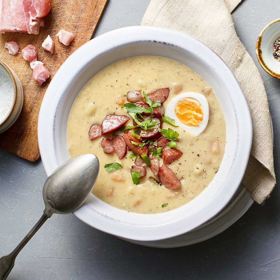 Cremige Suppe, getoppt mit Fleischstückchen, gekochtem Ei und gehackter Petersilie, in großen Suppentellern