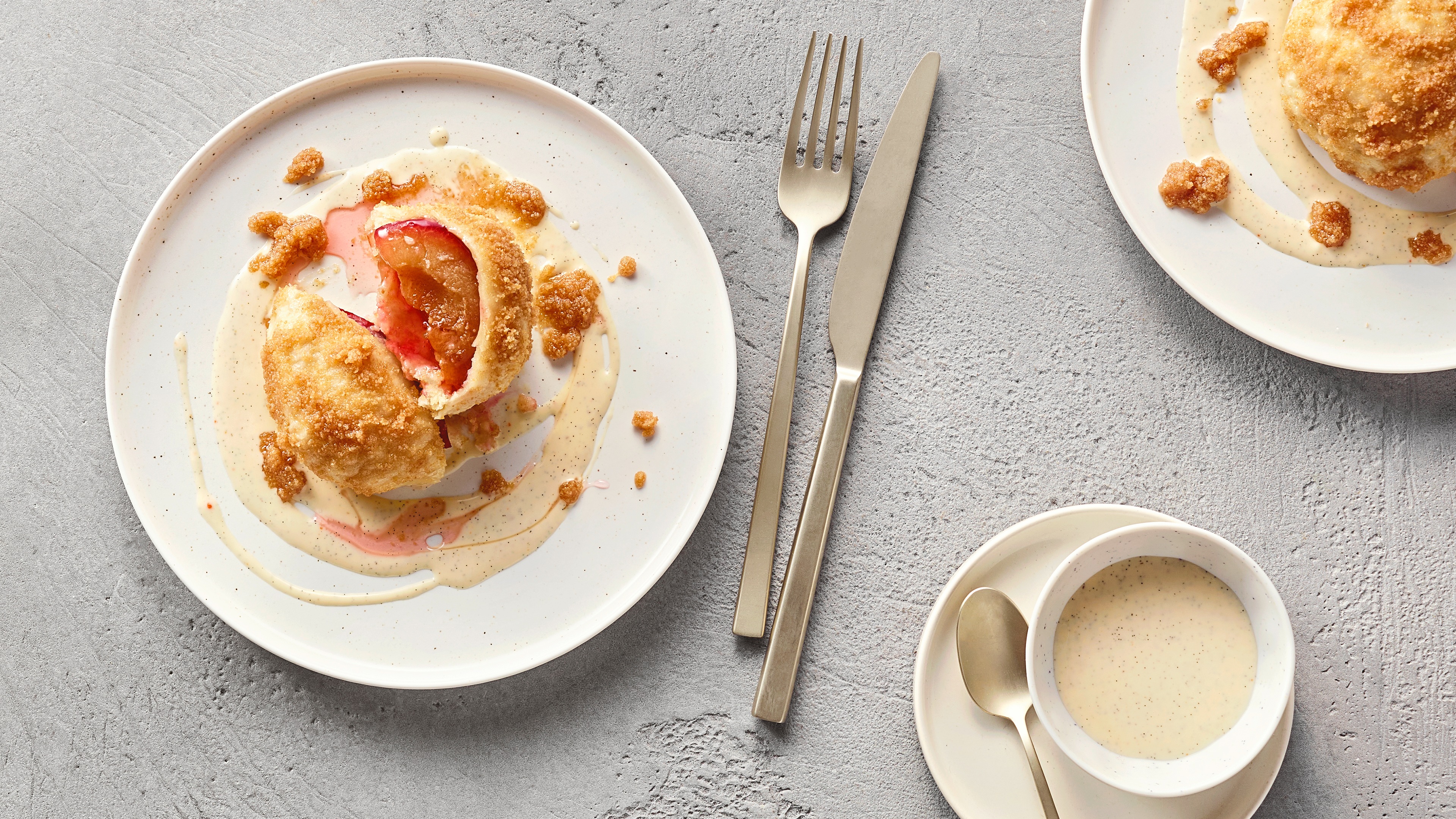 Geöffneter mit Früchten gefüllter Knödel auf Teller, daneben eine helle Soße
