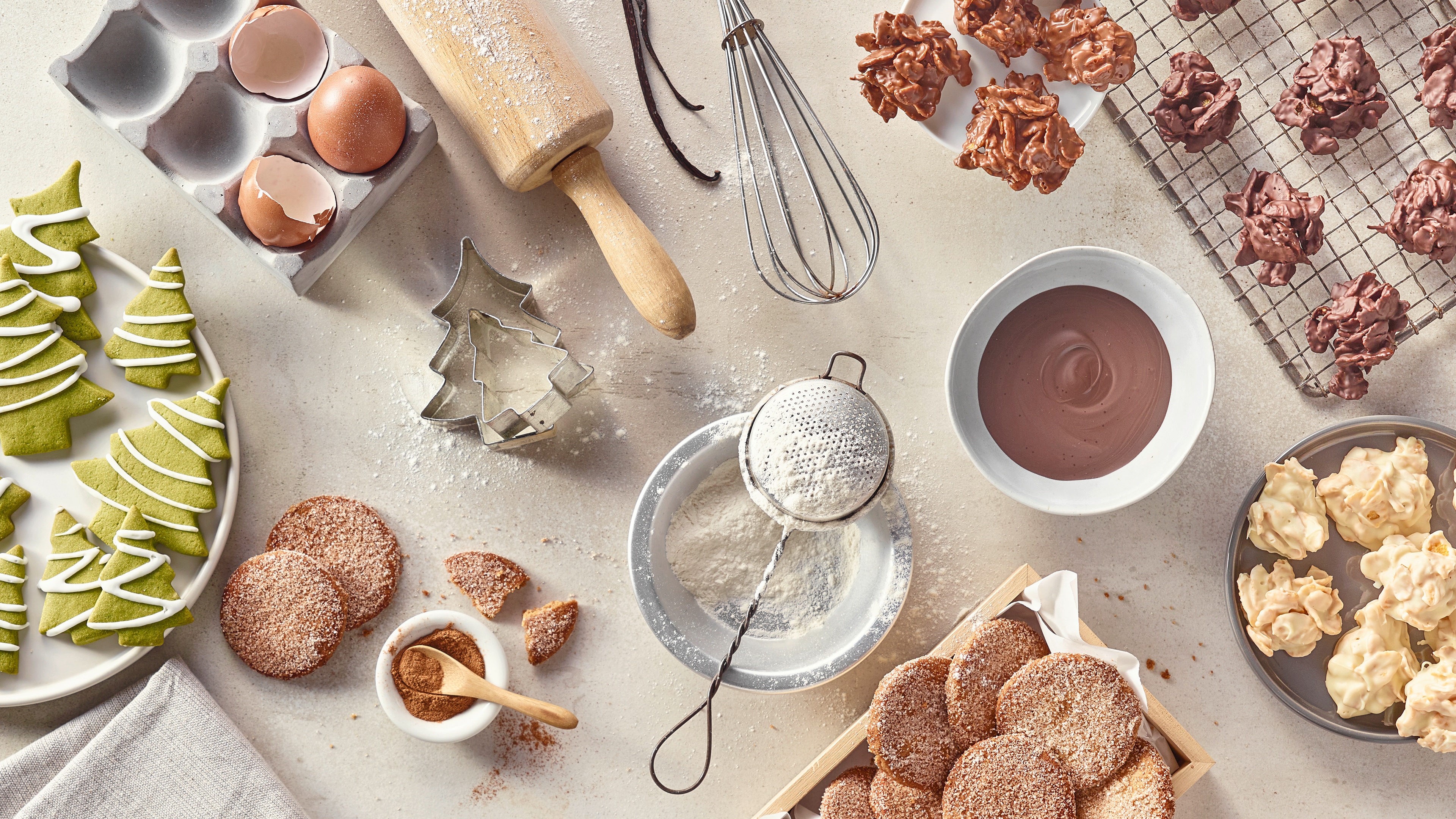 Gebackene Plätzchen und diverse Backutensilien auf hellem Untergrund