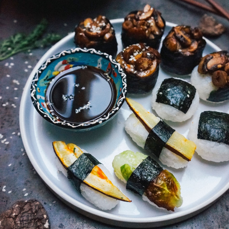 Verschiedene Gemüsesushi mit Sojasauce auf einem weißen Teller.