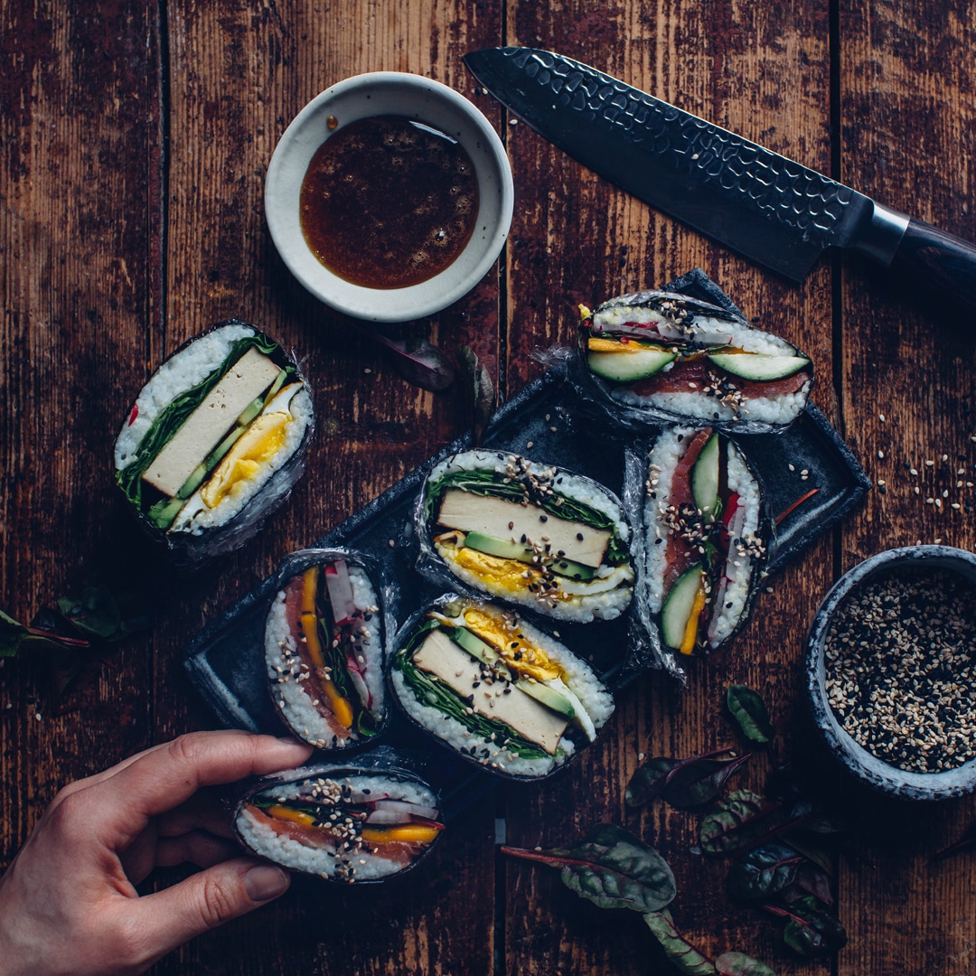 Sushi-Sandwiches mit Tofu, Gemüse und Sesam auf einem Holztisch.