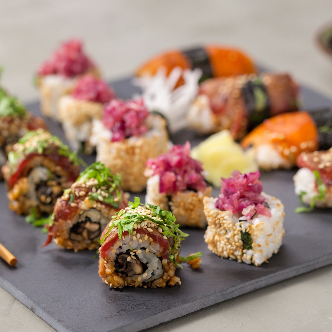 Verschiedene Sushi-Rollen und Nigiri auf einer dunklen Servierplatte.