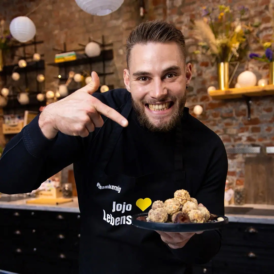 Junger Mann mit Bart präsentiert einen Teller voller Snack-Balls.