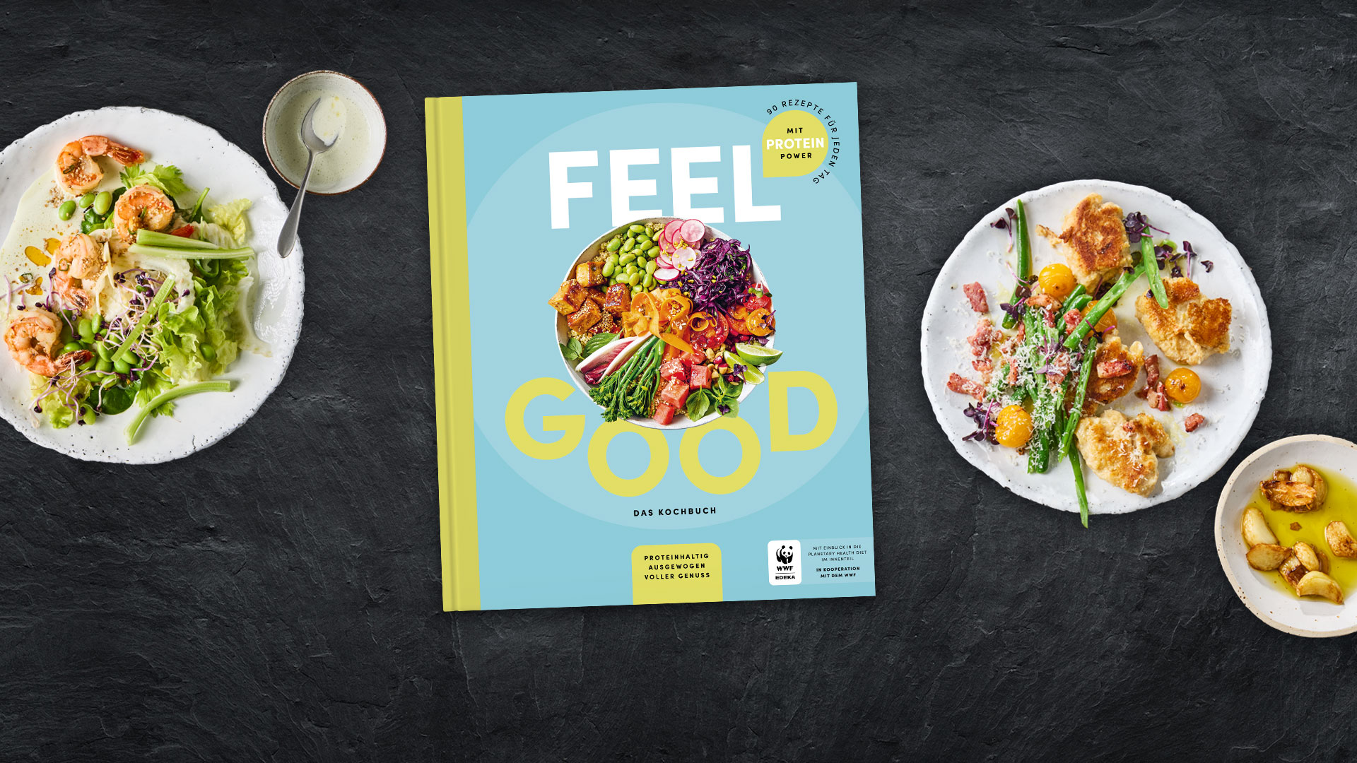 Kochbuch „Feel Good“, umgeben von Tellern mit verschiedenen Speisen.