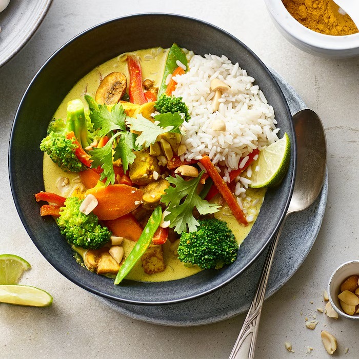 Curry mit Reis und Gemüse in einem tiefen Teller.