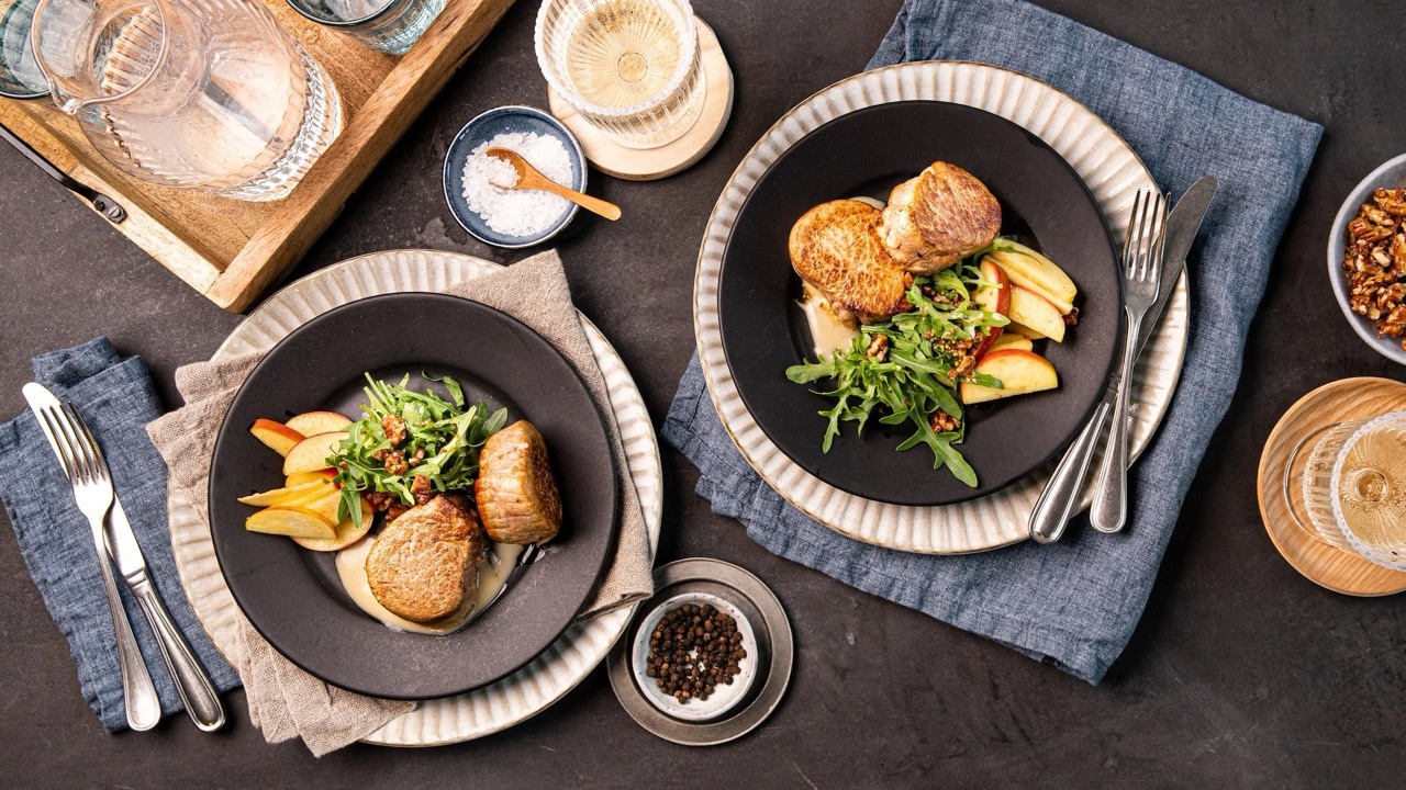 Schweinfilets mit Äpfeln auf zwei Tellern.