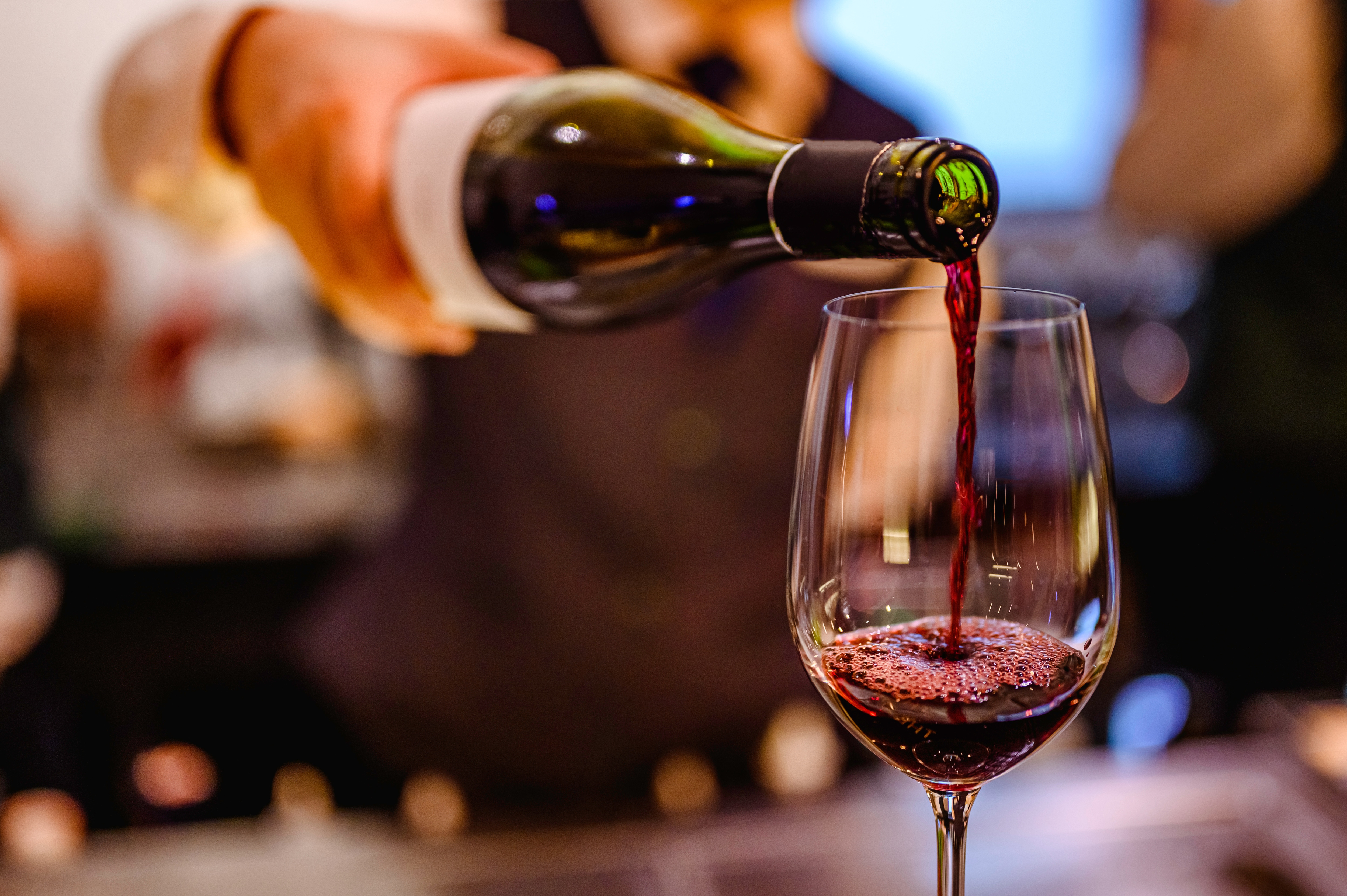 Weinglas wird mit Rotwein befüllt.