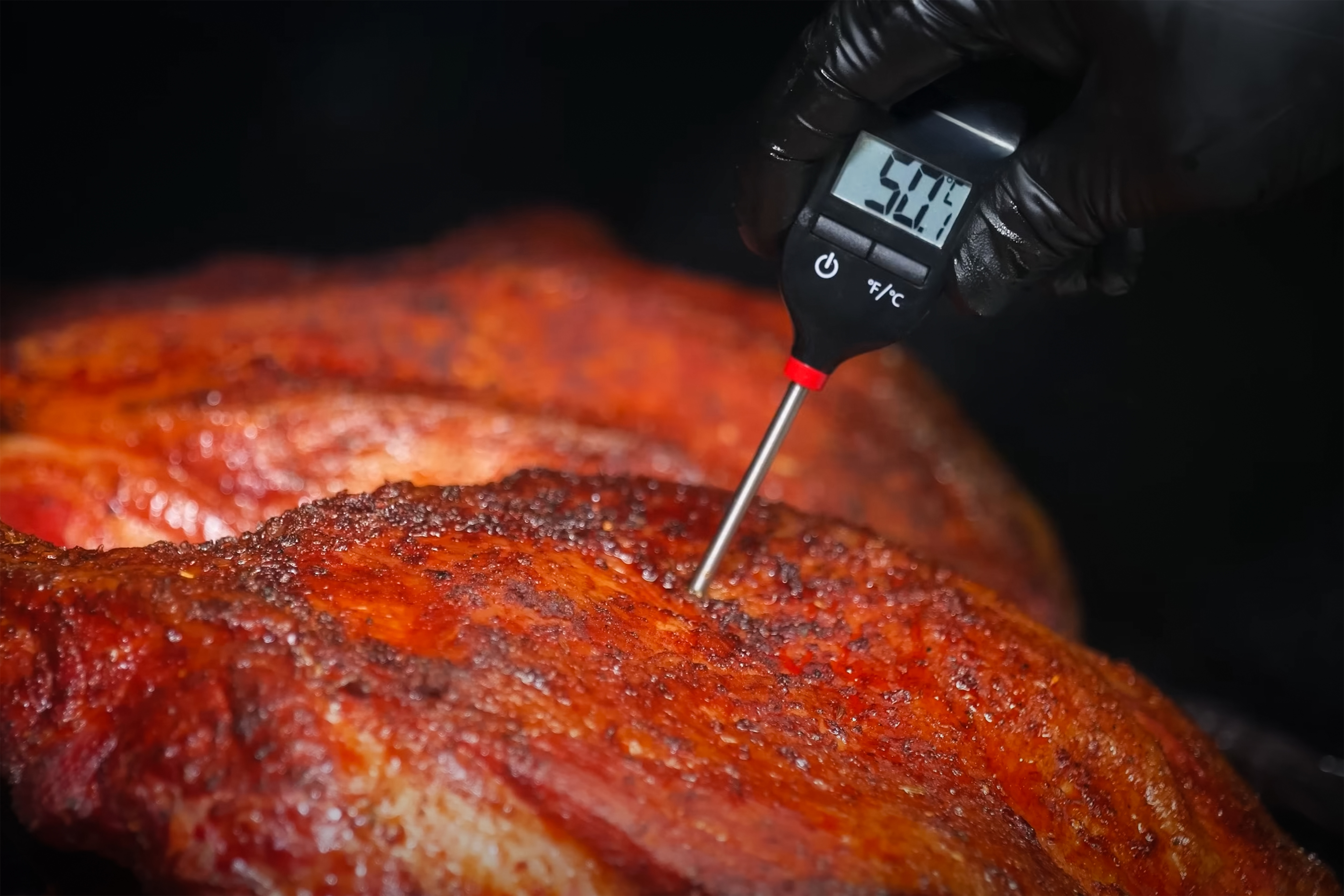 Fleischthermometer wird an Fleisch gehalten