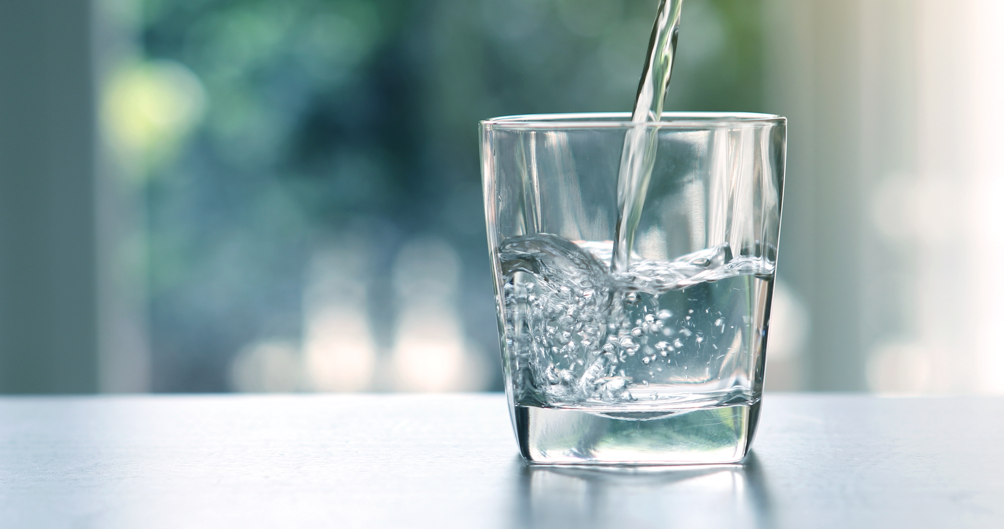 Nahaufnahme des Eingießens von gereinigtem, frischem Trinkwasser aus der Flasche.