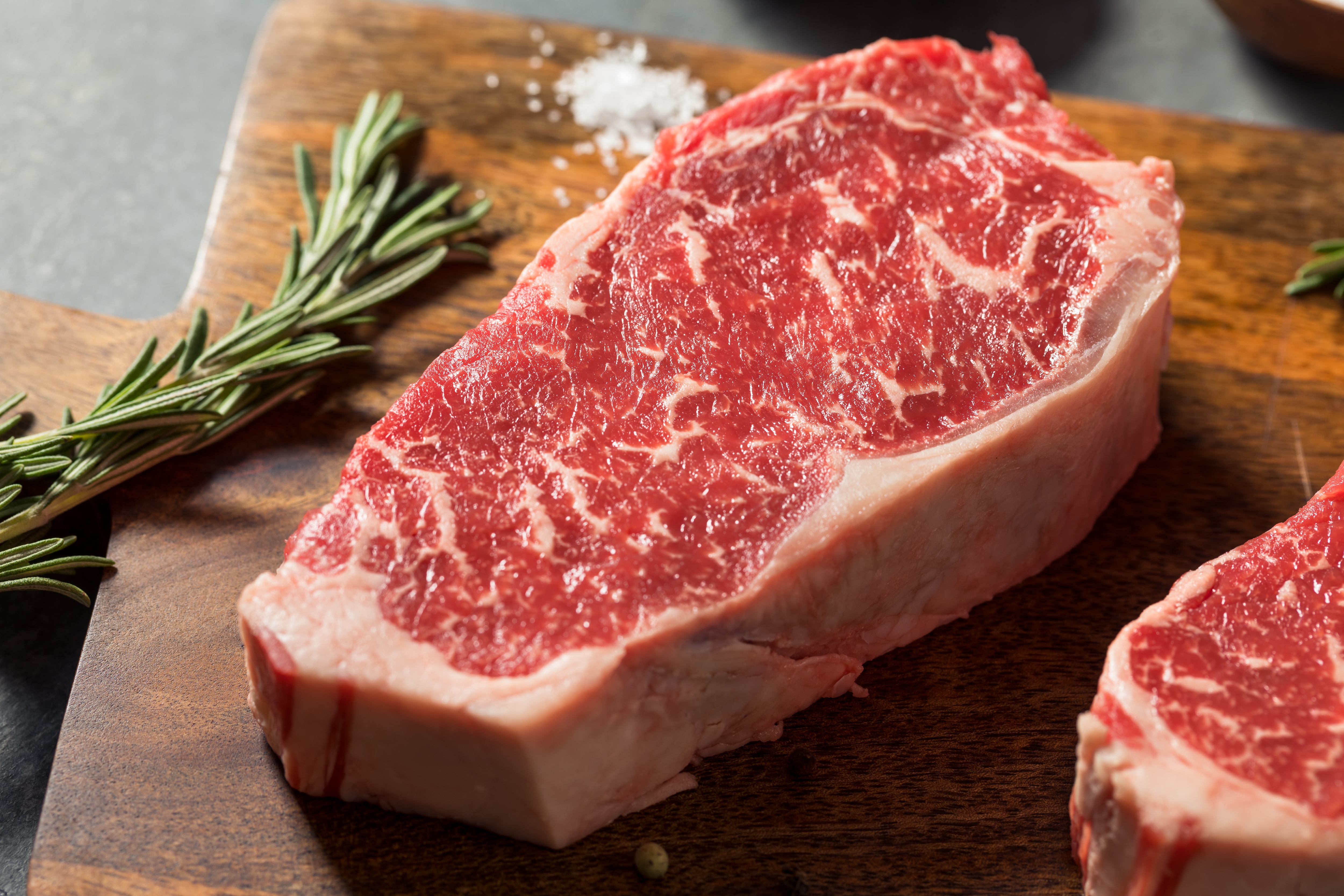Rohes Fleisch auf Brett mit Rosmarin und Salz