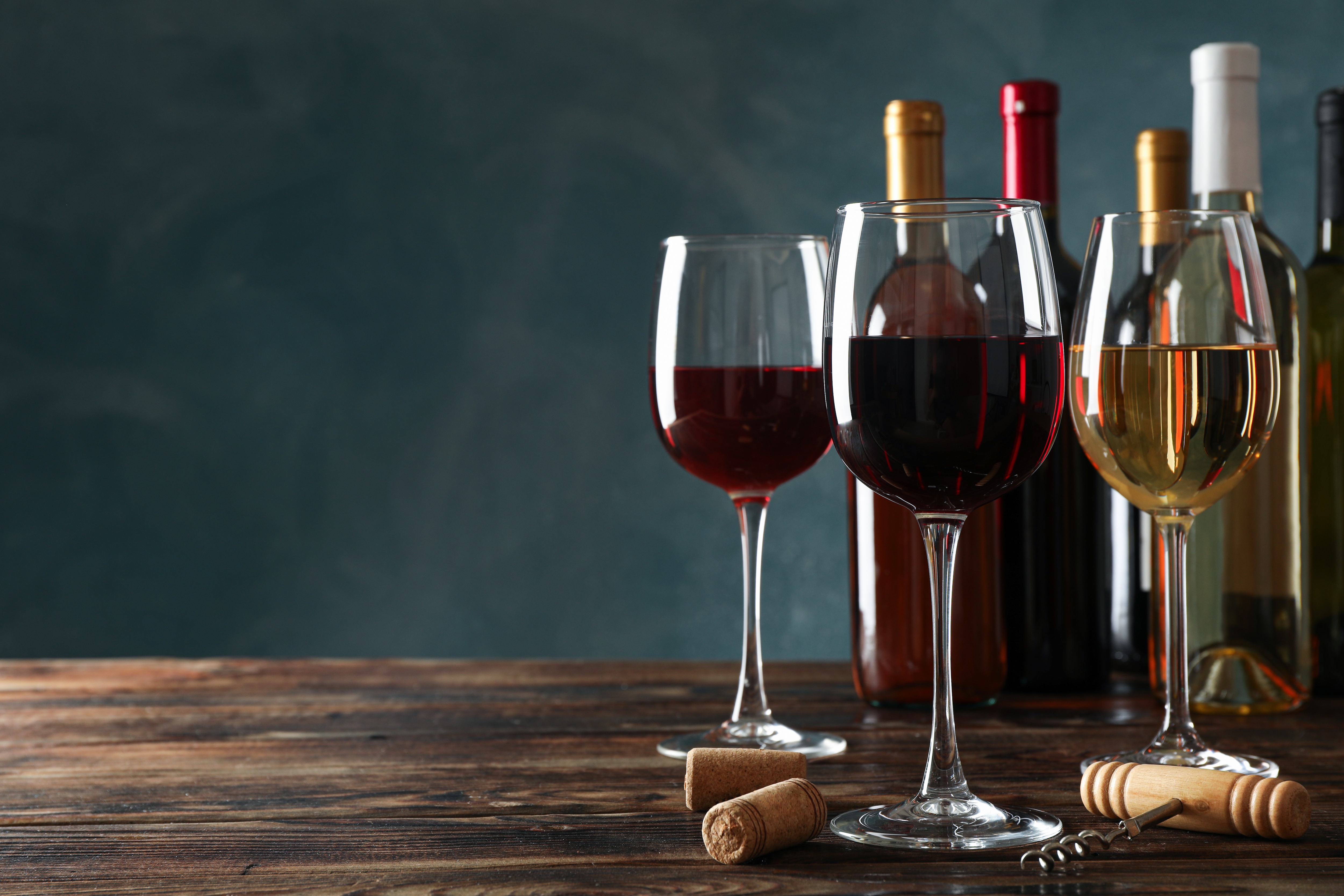 Verschiedene Weinsorten, Korken und Korkenzieher auf Tisch.