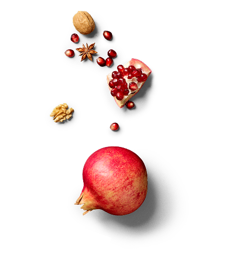Ein ganzer Granatapfel, Granatapfelkerne, sowie Walnüsse und Sternanis von oben fotografiert.